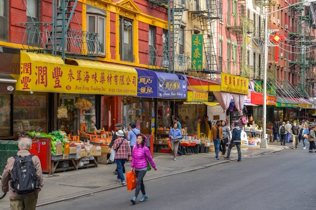 People walking past colorful storefronts in the Chinatown district of Manhattan