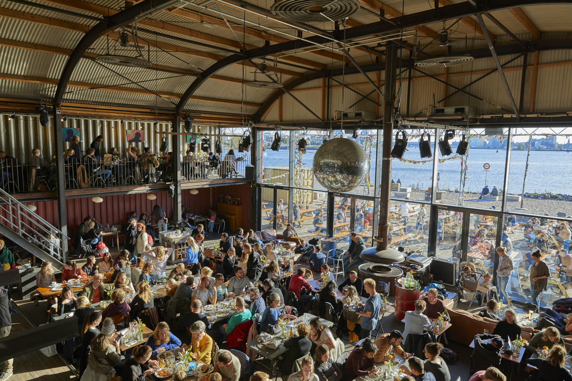 The crowded beer hall filled with drinkers during the day at Pillek Cafe, NDSM wharf, Noord, Amsterdam, Netherlands