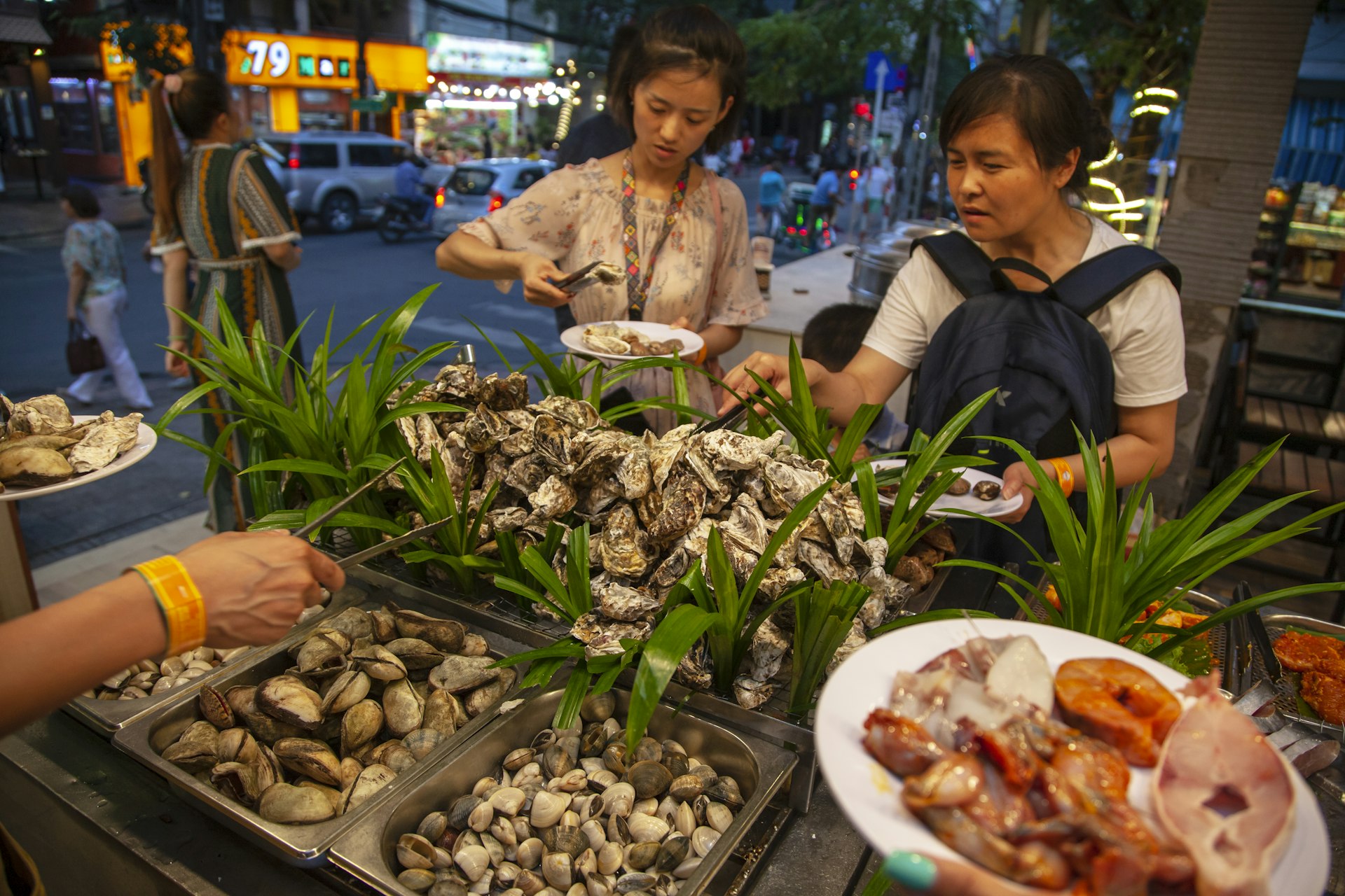Two women get fresh oysters, shrimp and other seafood at a street-food market in Phuket Town, Phuket, Thailand