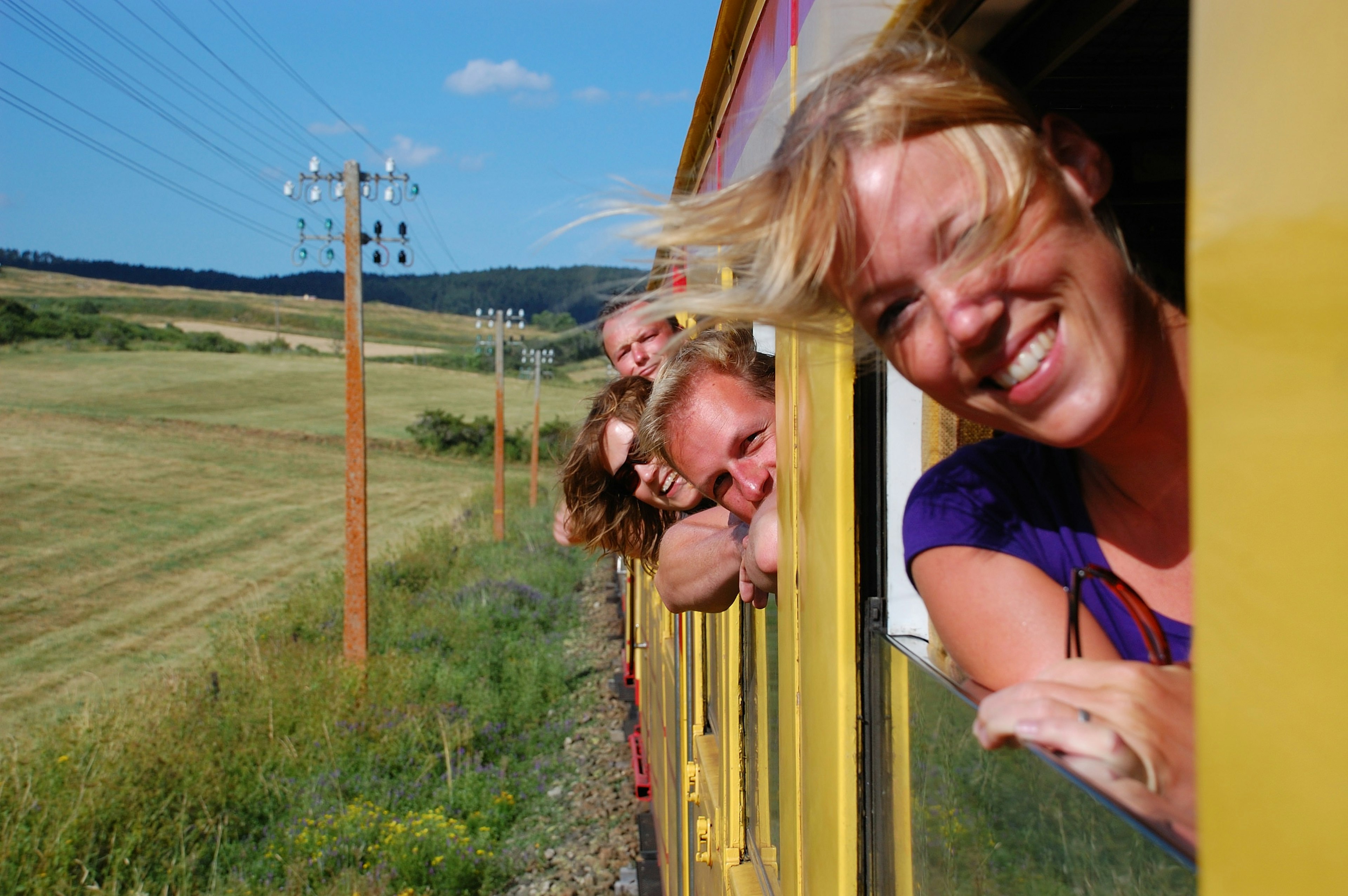 Travelers leaning out the windows of the yellow train in the Pyrenees