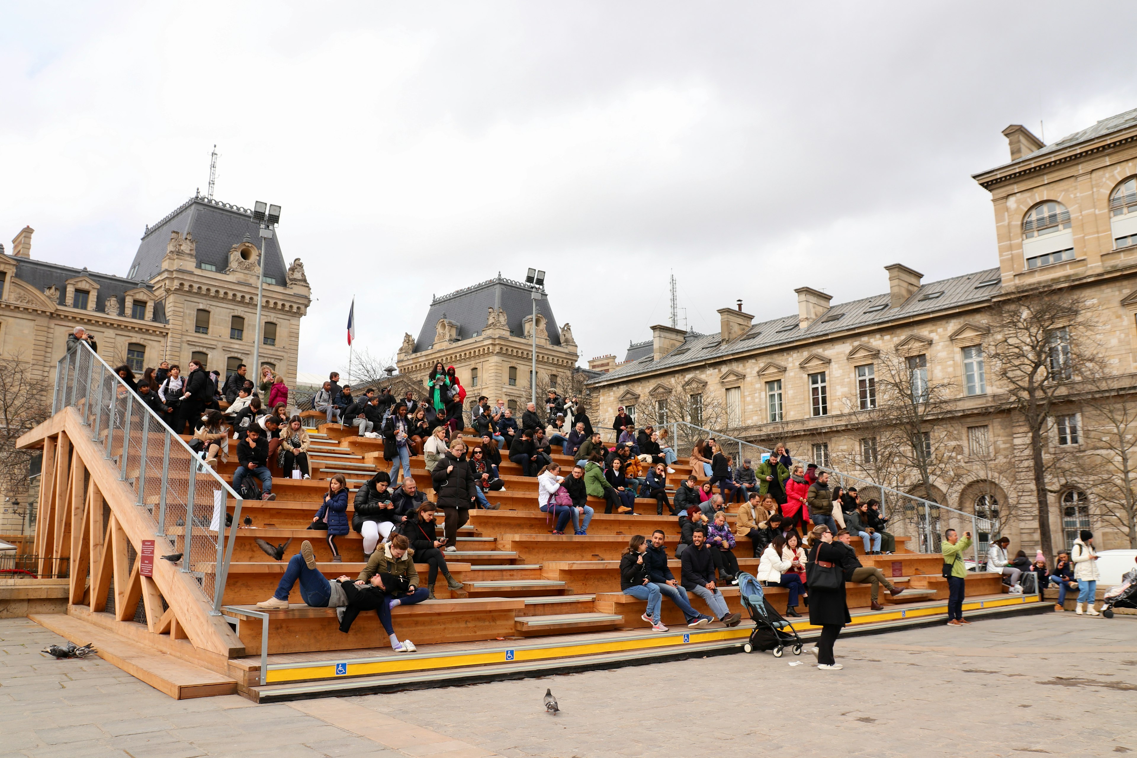 People sit on bleachers in a historic area of Paris.