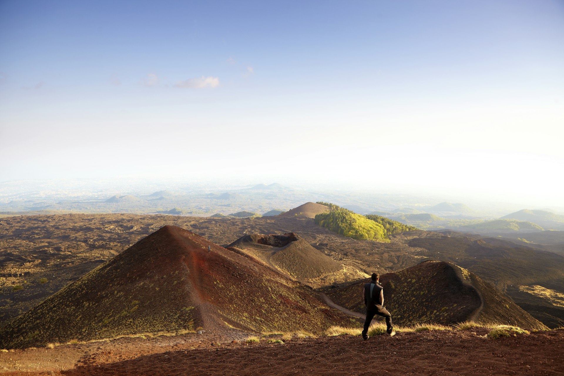 Un geologo in piedi sul versante orientale dell'Etna, affacciato sulla campagna