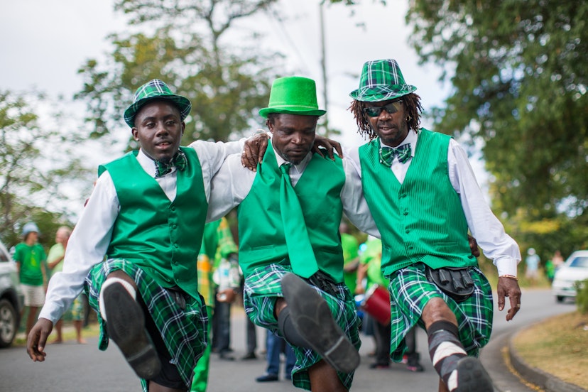A trio of men dressed like leprechauns kick up their legs during Montserrat's annual St. Patrick's Day celebration.
