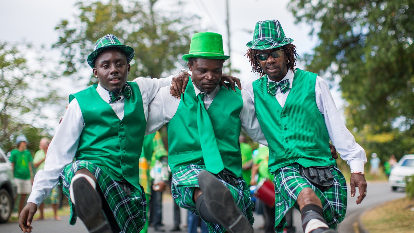 A trio of men dressed like leprechauns kick up their legs during Montserrat's annual St. Patrick's Day celebration.