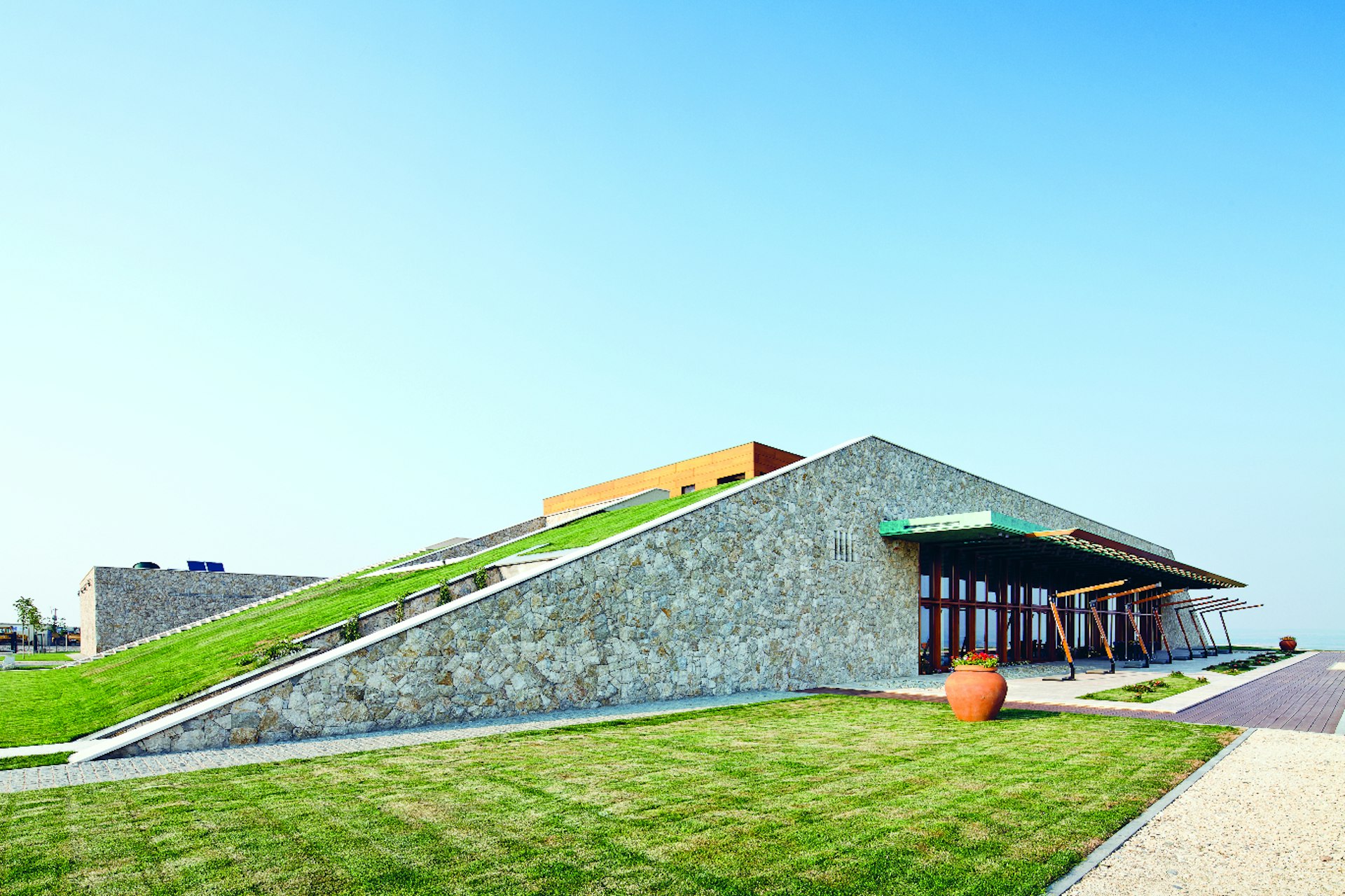 The exterior of a wine-tasting room, with a sloped roof covered in grass