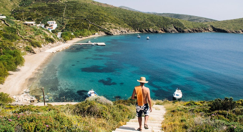 Rear view of a man walking down to a beach on Fourni Island, Greece.