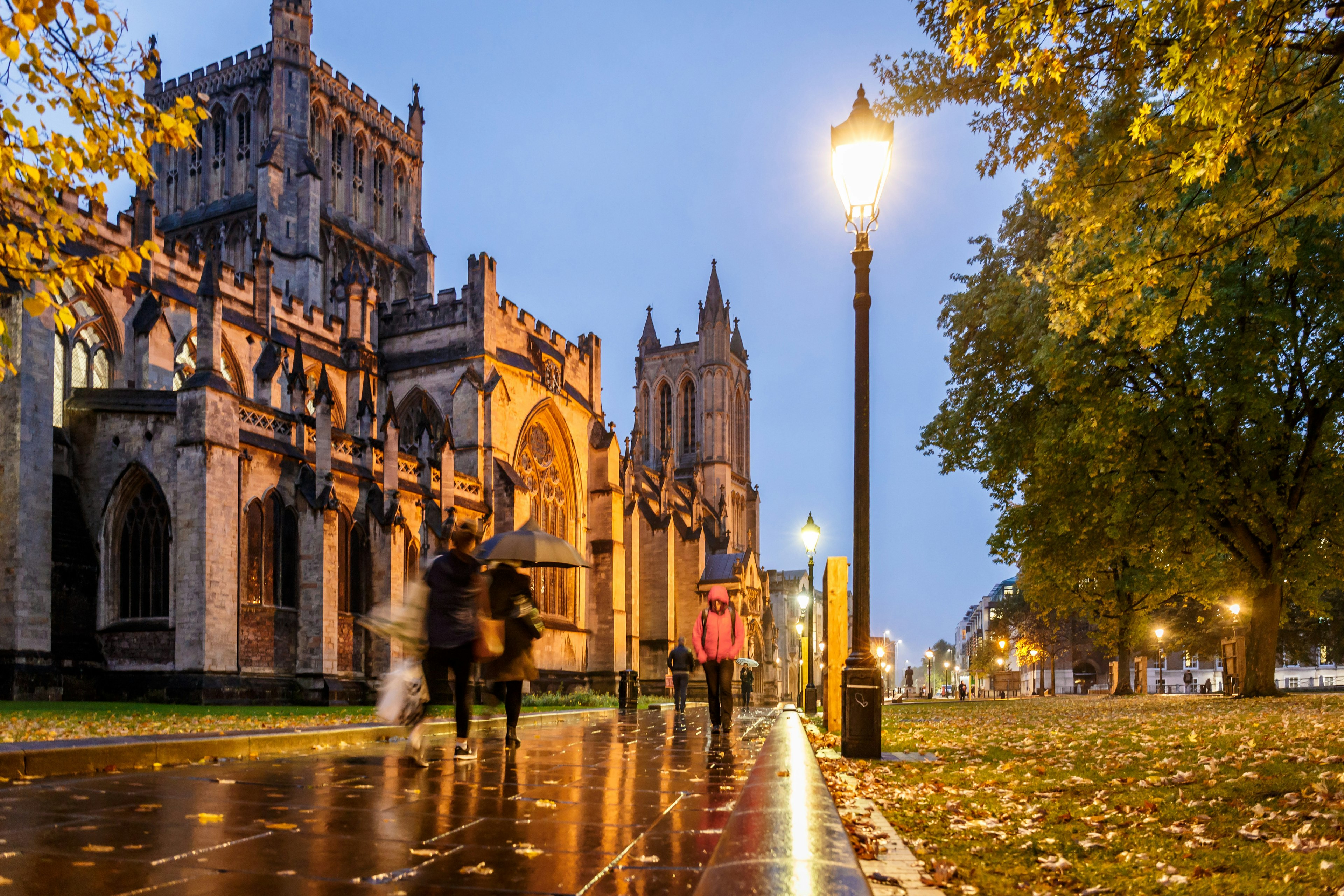 People in coats hurry through the rain on an autumn day