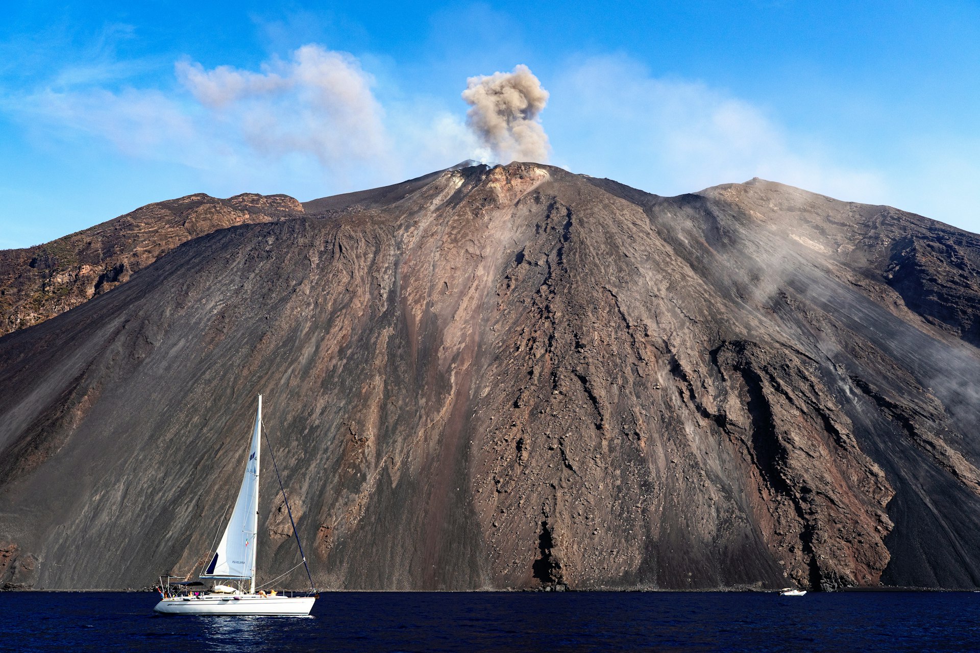 A sailboat passes by an eruption on Stromboli, Aeolian Islands, Italy