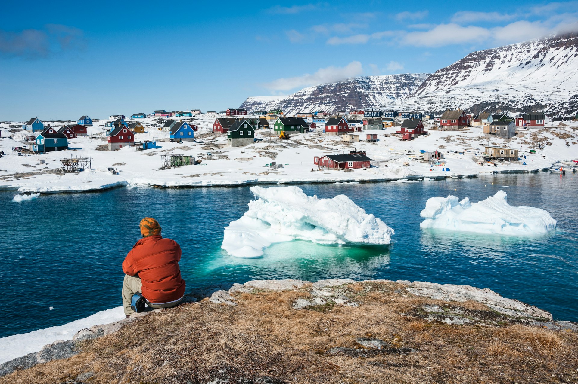 Rear view of a man sat admiring wonderful views of Qeqertarsuaq, a small town in Greenland 