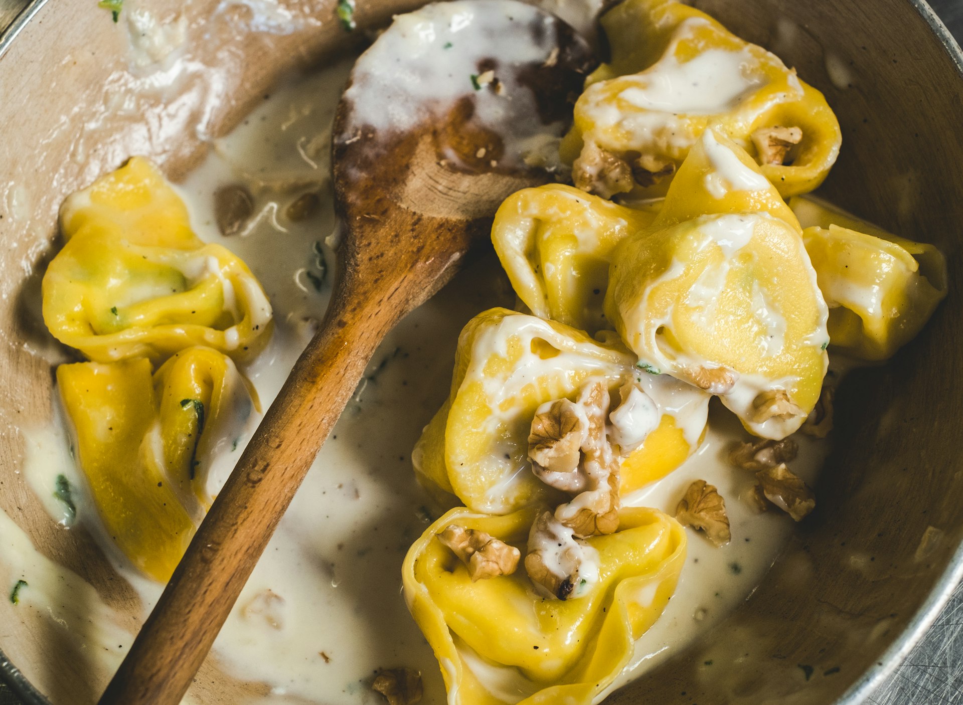 Tortelloni (typical Bologna homemade stuffed pasta) with nuts, cream and sage in their cooking pan