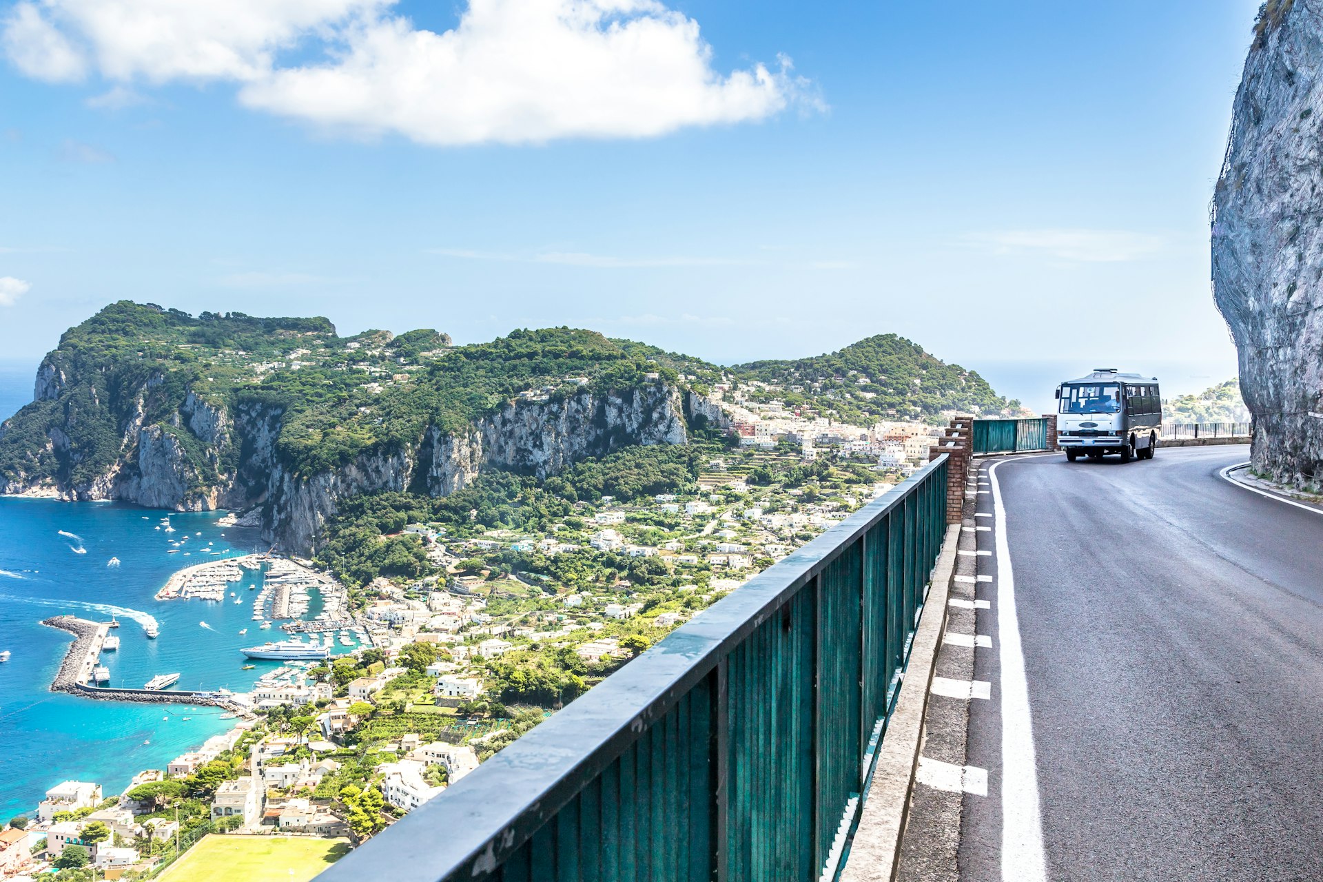 A bus on a curved road against a rocky cliff in the Amalfi Coast, Catania, Italy