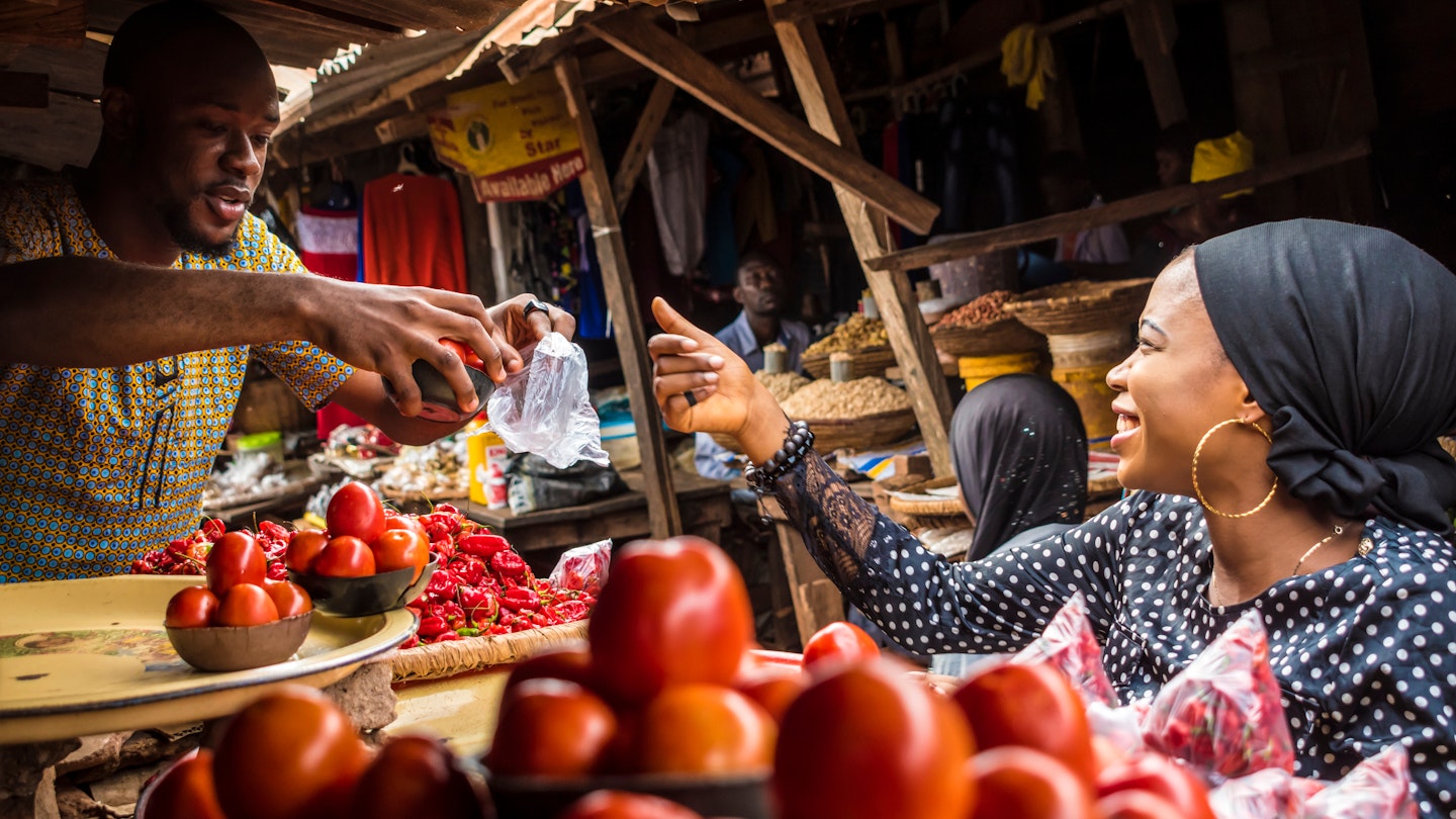 a guy selling tomatoes to a girl in a typical local african market; Shutterstock ID 1107623456; your: ClaireN; gl: 65050; netsuite: Online ed; full: Nigeria things to know
1107623456