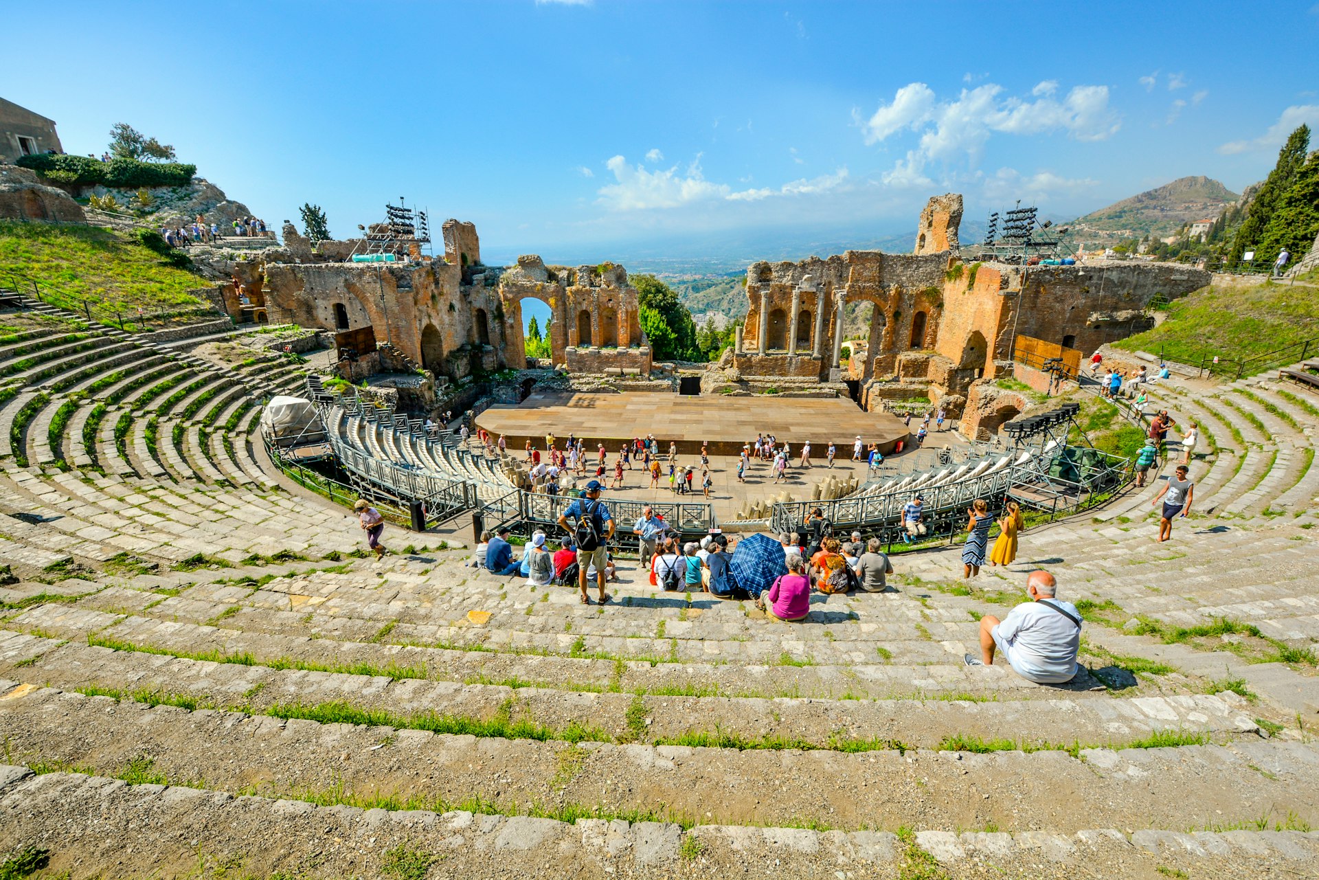 I turisti si godono un pomeriggio estivo nell'antico teatro greco della Sicilia nella località turistica di Taormina, in Italia