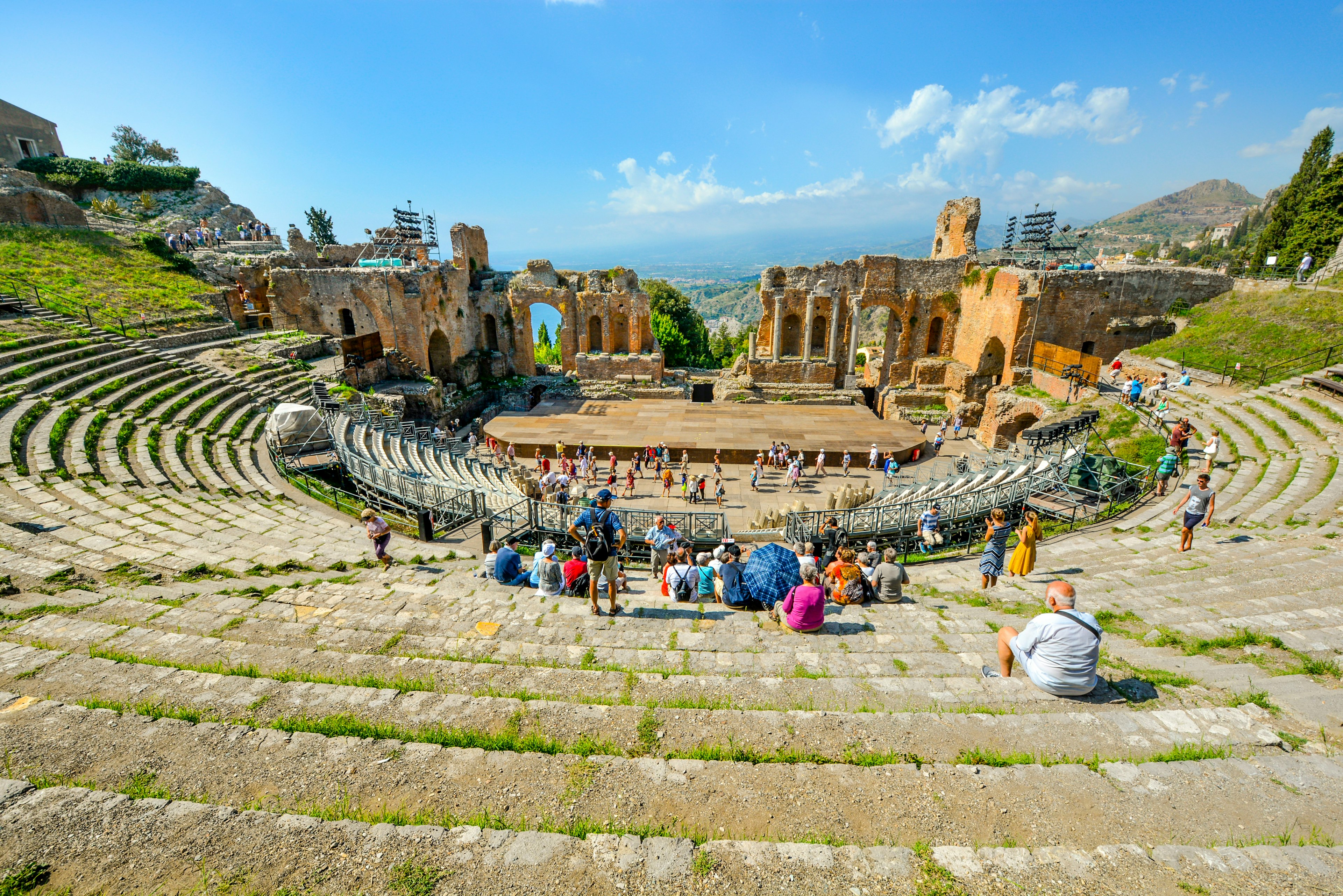 Tourists enjoy a summer afternoon at the ancient Greek Theatre on the Sicily at the resort city of Taormina, Italy