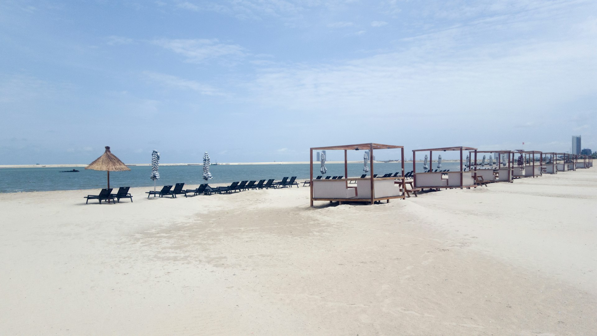 Cabins and sunloungers line a long empty beach