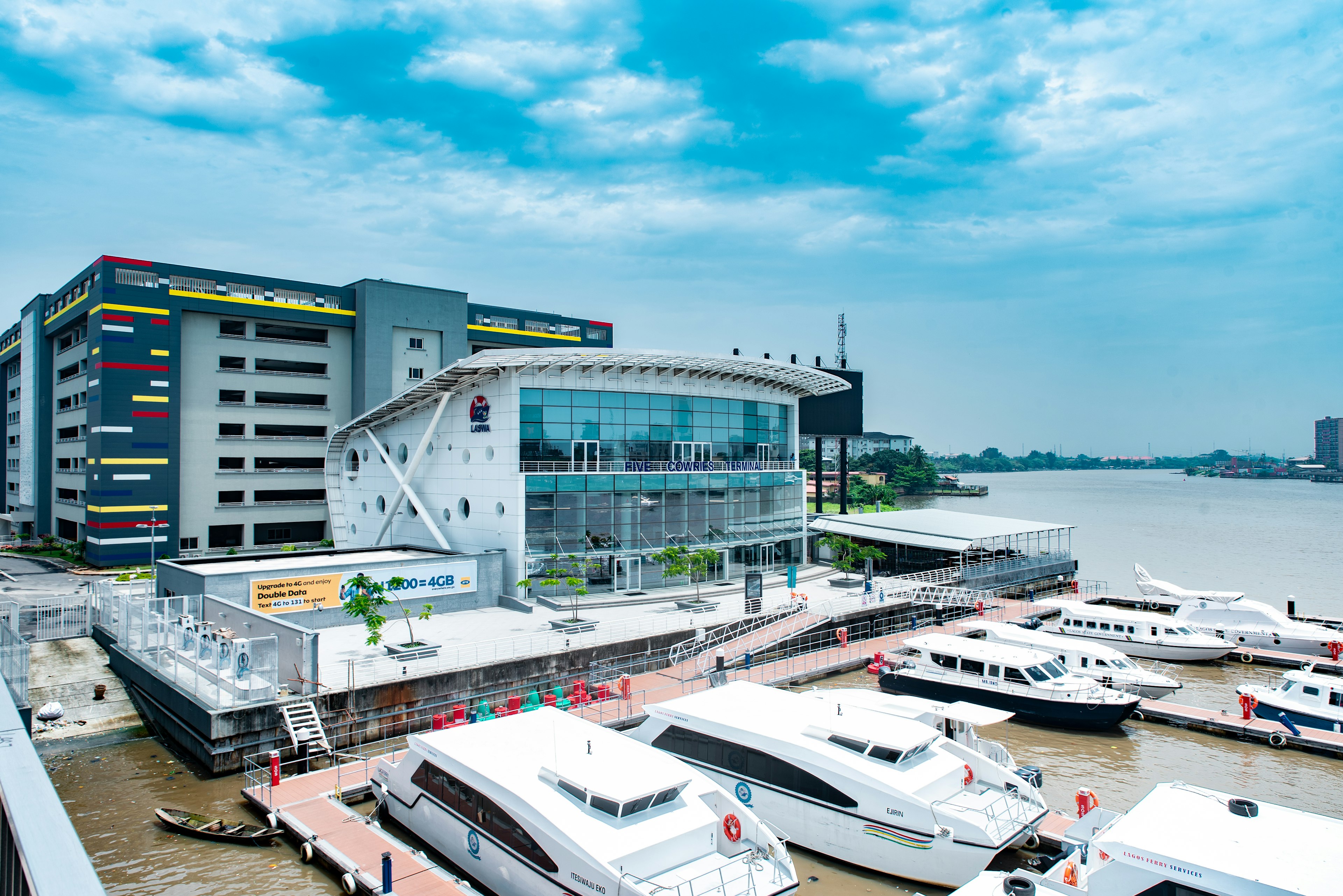 A series of modern ferries docked outside a large glass-fronted ferry terminal