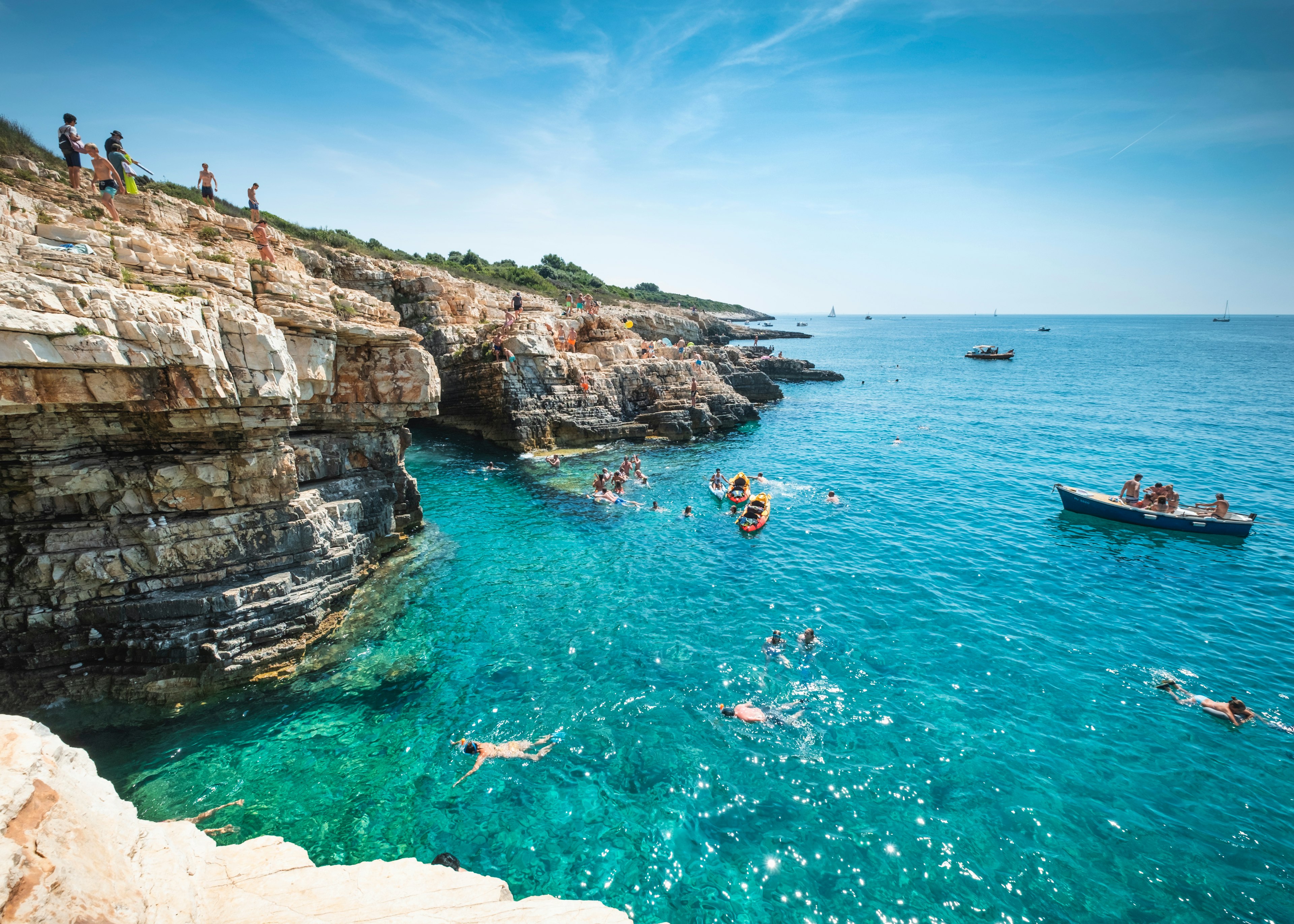 Boys dive into the sea from a cliff in Premantura, Croatia, Europe