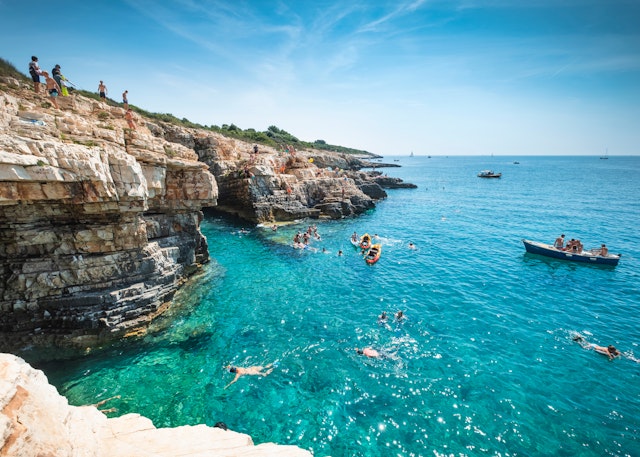 Boys dive into the sea from a cliff in Premantura, Croatia, Europe