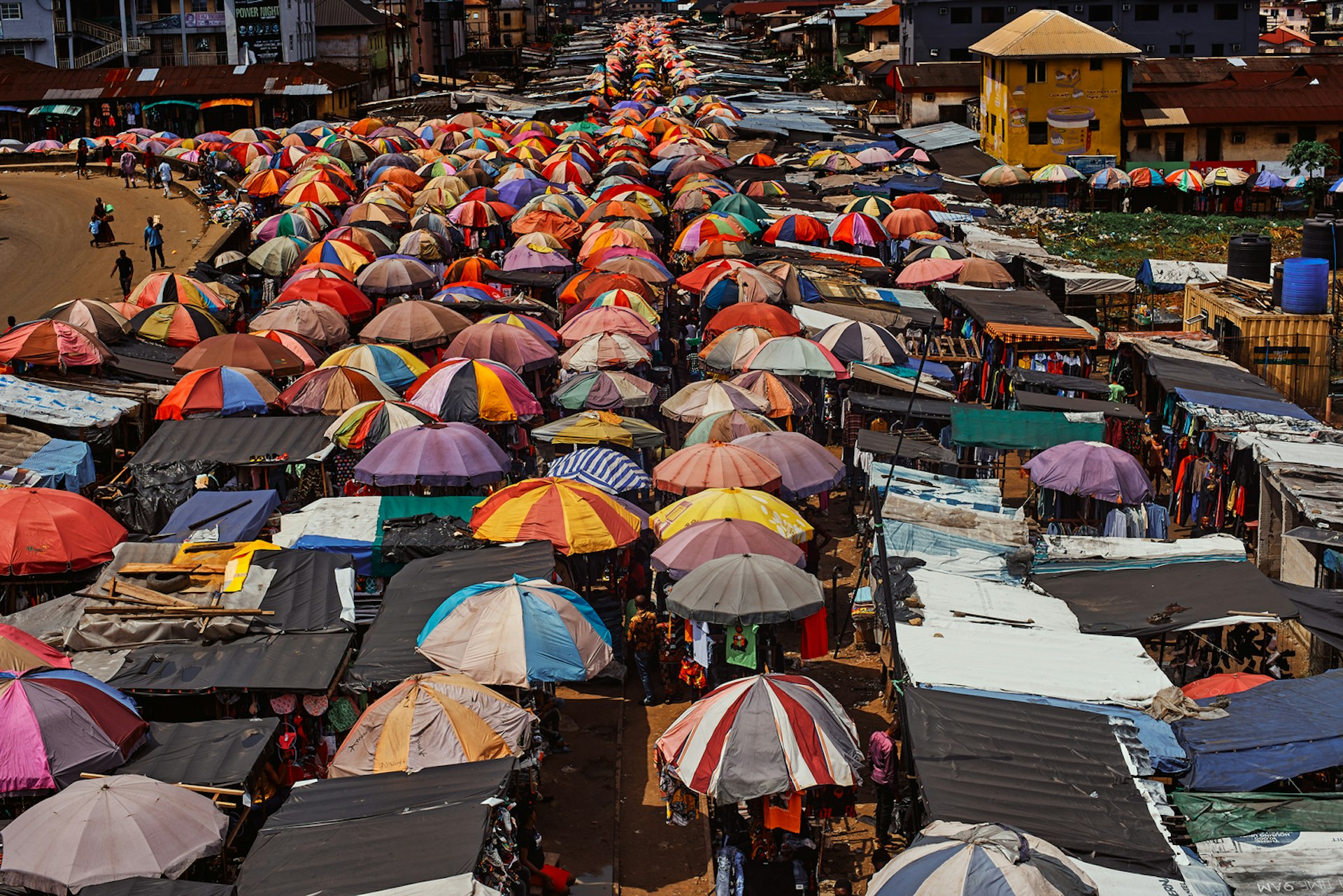 Hundreds of brightly colored umbrellas provide shade to shoppers at a busy market place