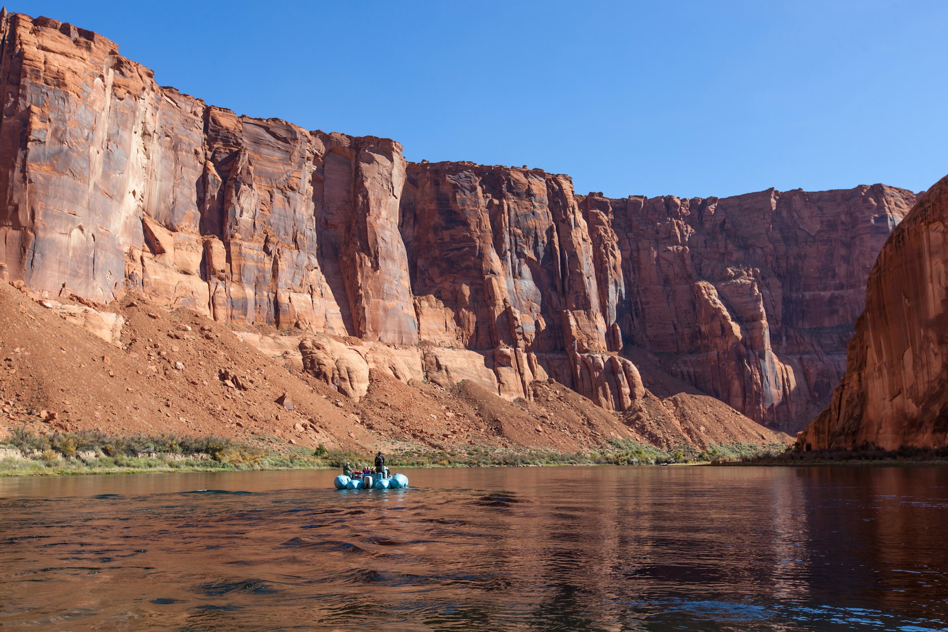 People rafting on a calm area of the Colorado River through Horseshoe Bend in Glen Canyon on a clear sunny day