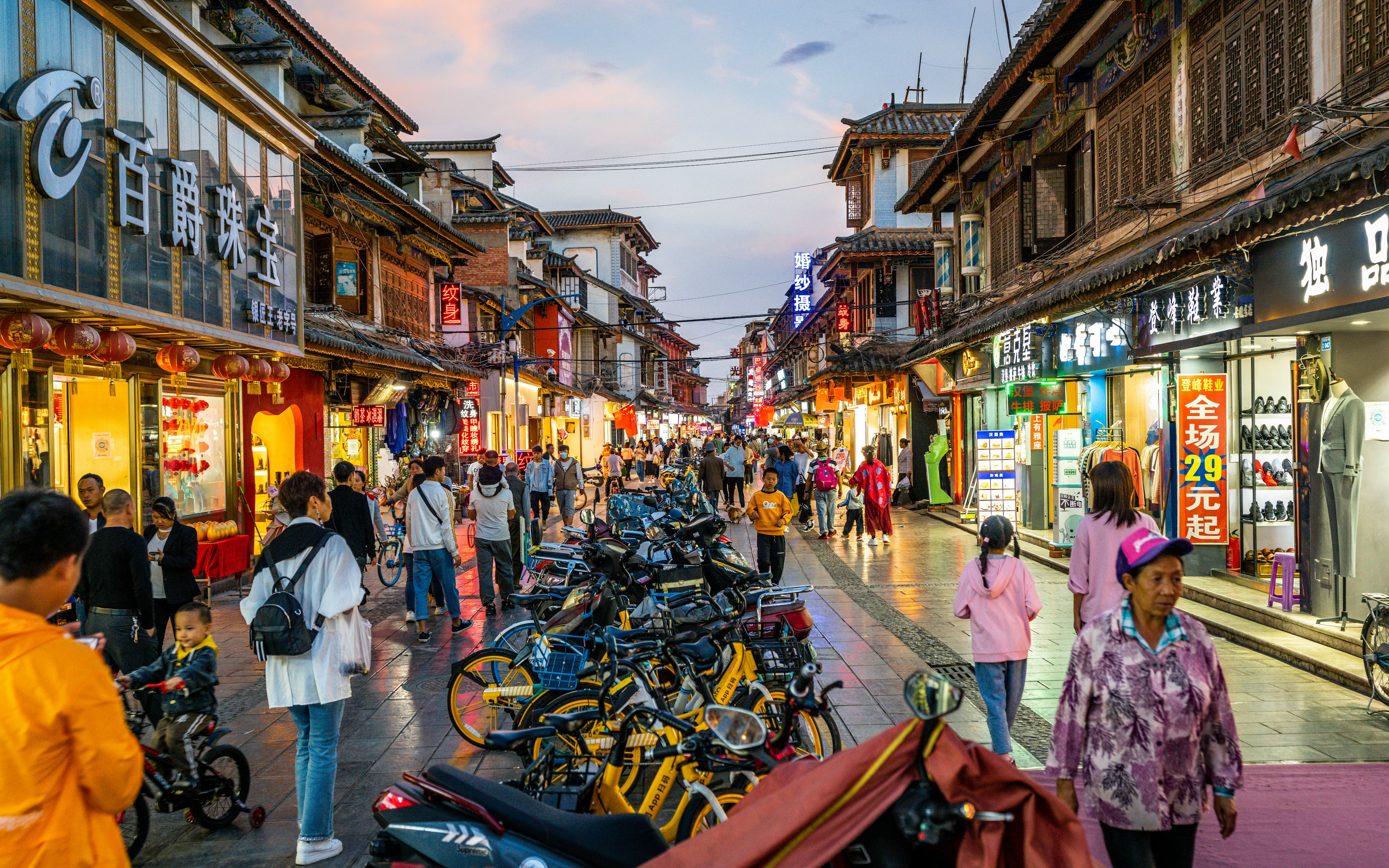 A view of crowds at dusk on a busy street in Guandu, Kunming, Yunnan, China