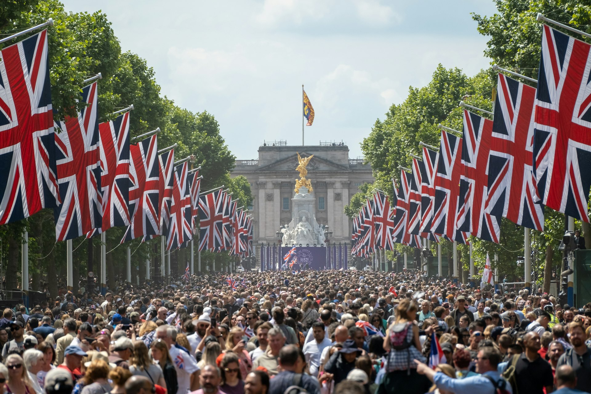 Crowds of people holding Union Jack flags on the Mall leading to Buckingham Palace, London, England, United Kingdom