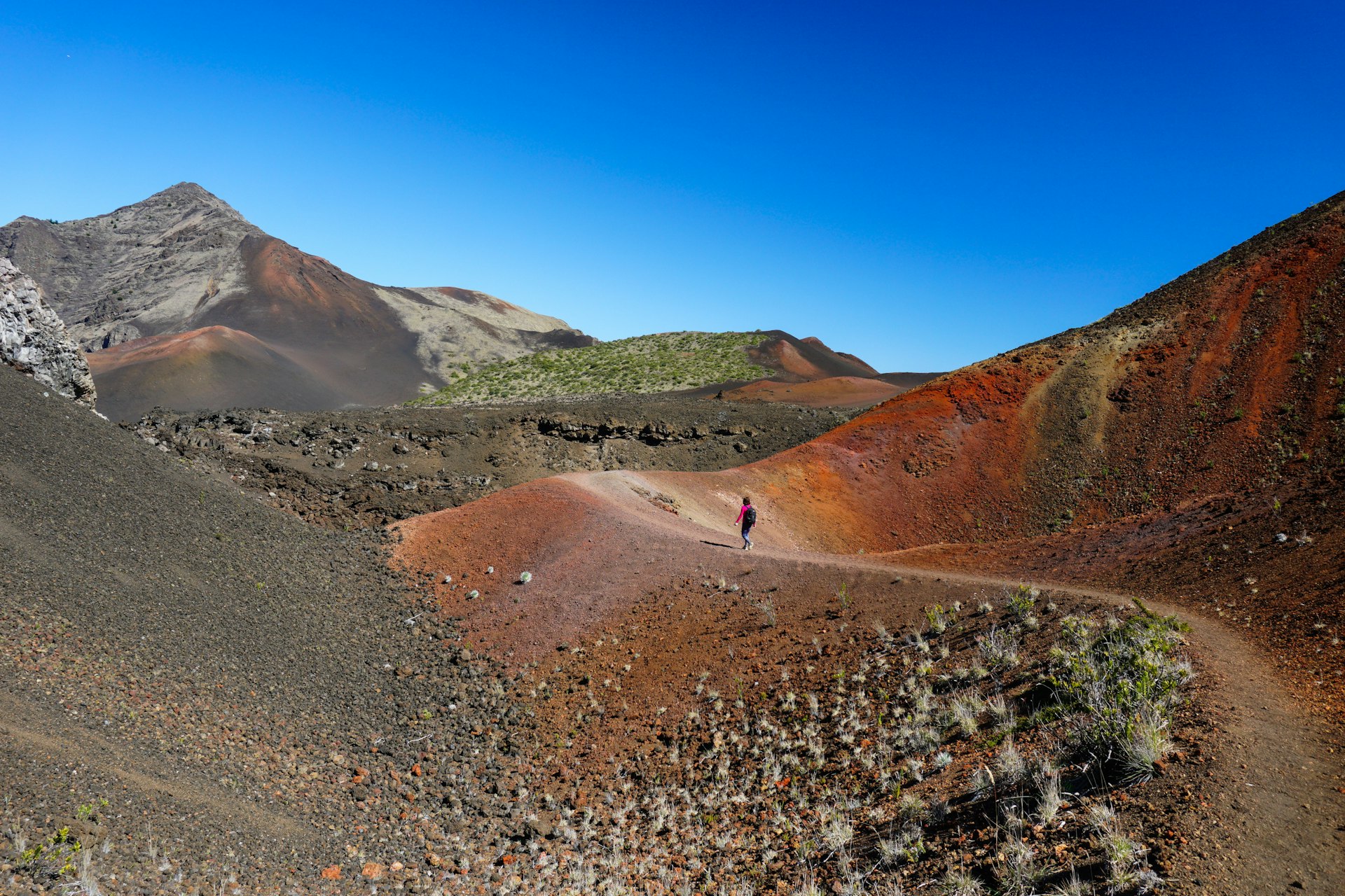 A person seen in the distance walking through the colorful landscape of Haleakala National Park, Hawaii