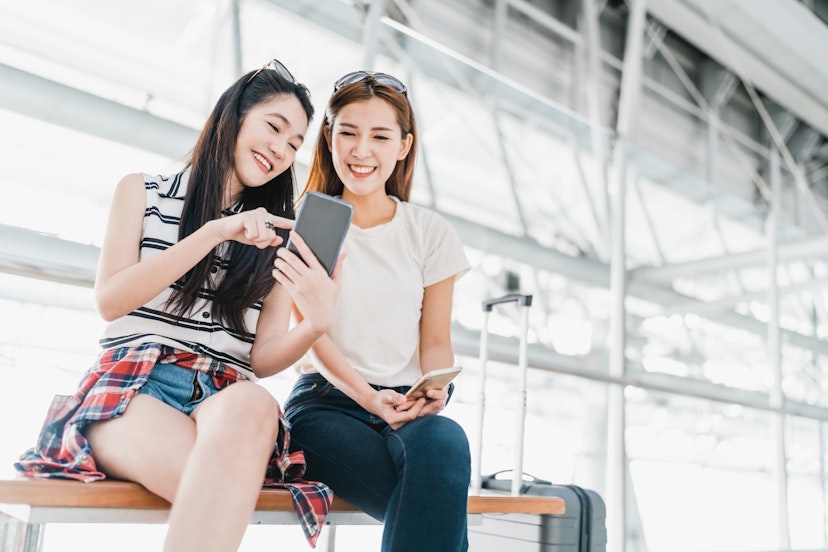 Two happy Asian girls using smartphone checking flight or online check-in at airport together, with luggage. Air travel, summer holiday, or mobile phone application technology concept; Shutterstock ID 624203687; your: Ben N Buckner; gl: 65050; netsuite: Online Editorial; full: Ben Buckner - Chase Southwest
624203687