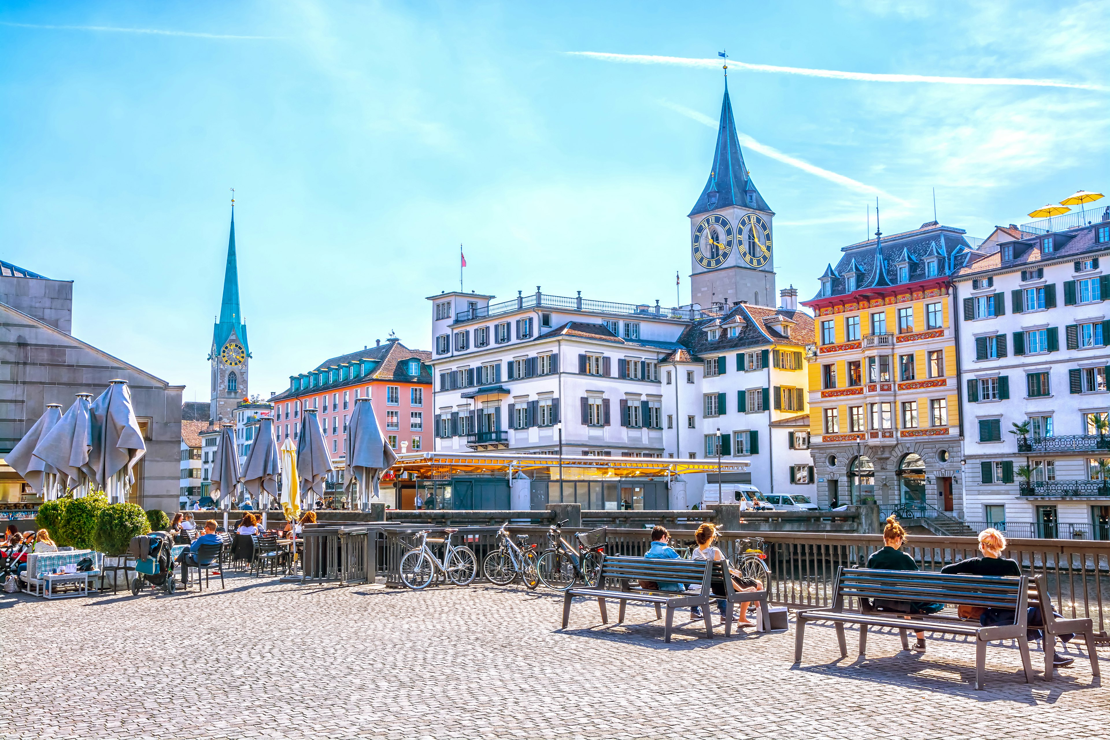 People relax on benches and in at street cafe on the Limmat River in Zurich.