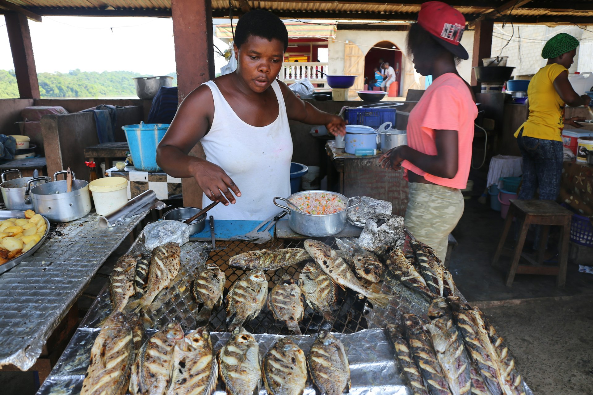 A woman grilling fish at a traditional restaurant, Ndjolé, Gabon, Africa
