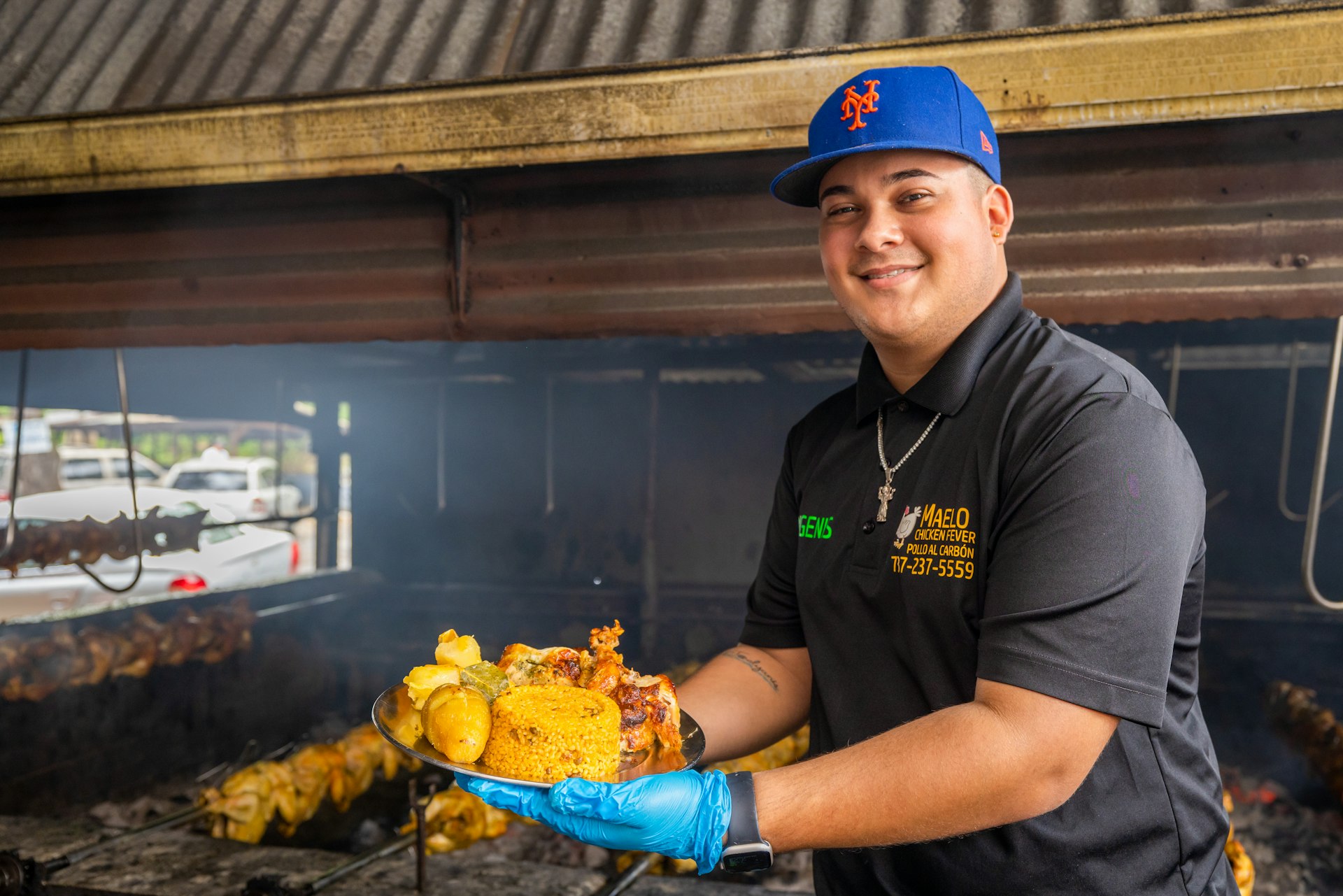 Man holds up a plate of food, he is wearing a baseball cap, and a blue plastic hygiene glove, Puerto Rico