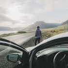 Young Caucasian woman in purple coat  looking at scenic landscape in Iceland near the car
1055479098