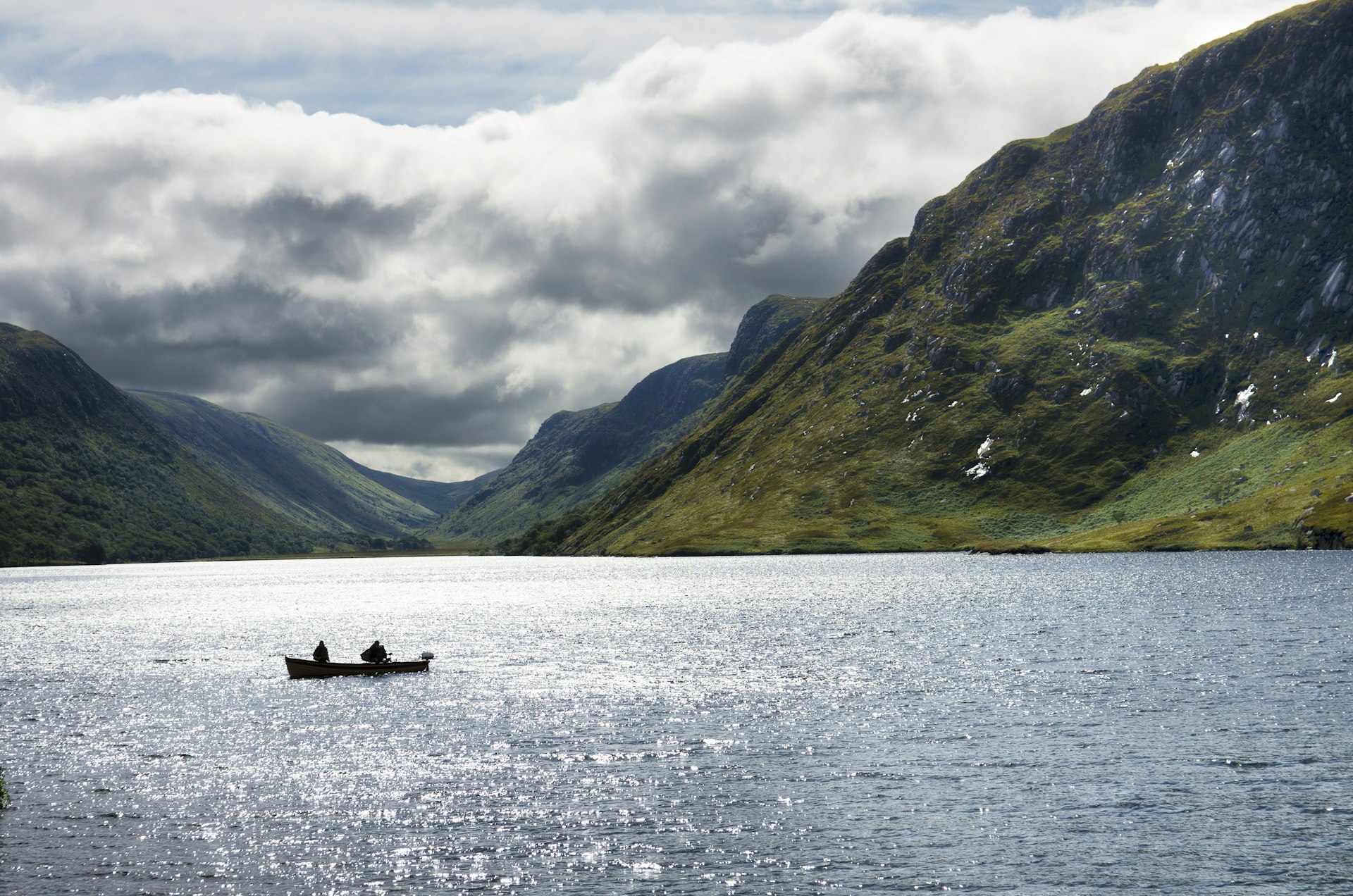 People canoe on a lake in Glenveagh National Park, framed by green mountains