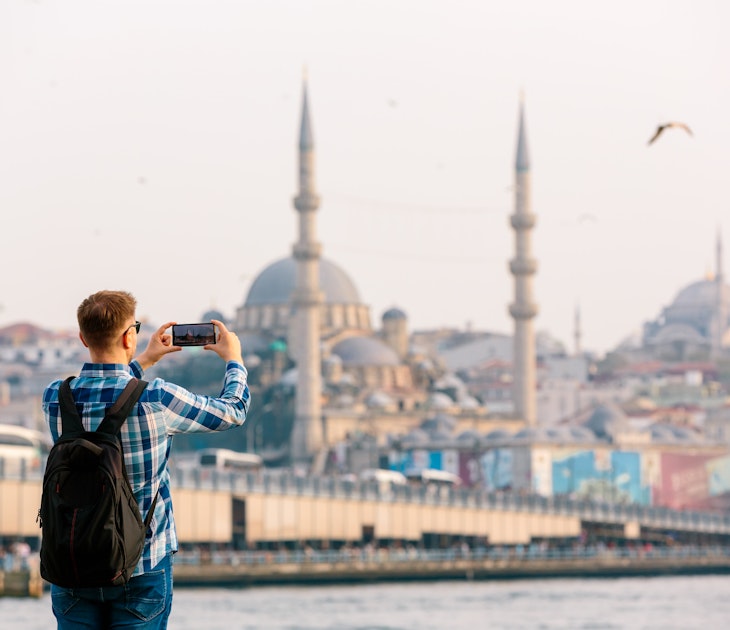 Tourist photographing Istanbul skyline with smart phone, rear view - stock photo