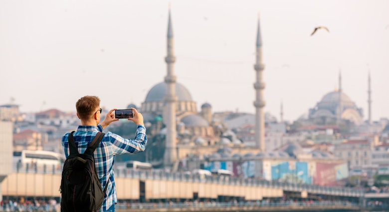 Tourist photographing Istanbul skyline with smart phone, rear view - stock photo