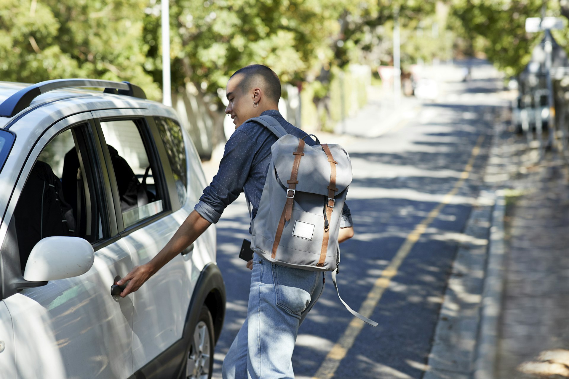 A guy wearing a backpack opening a car door in Cape Town, South Africa