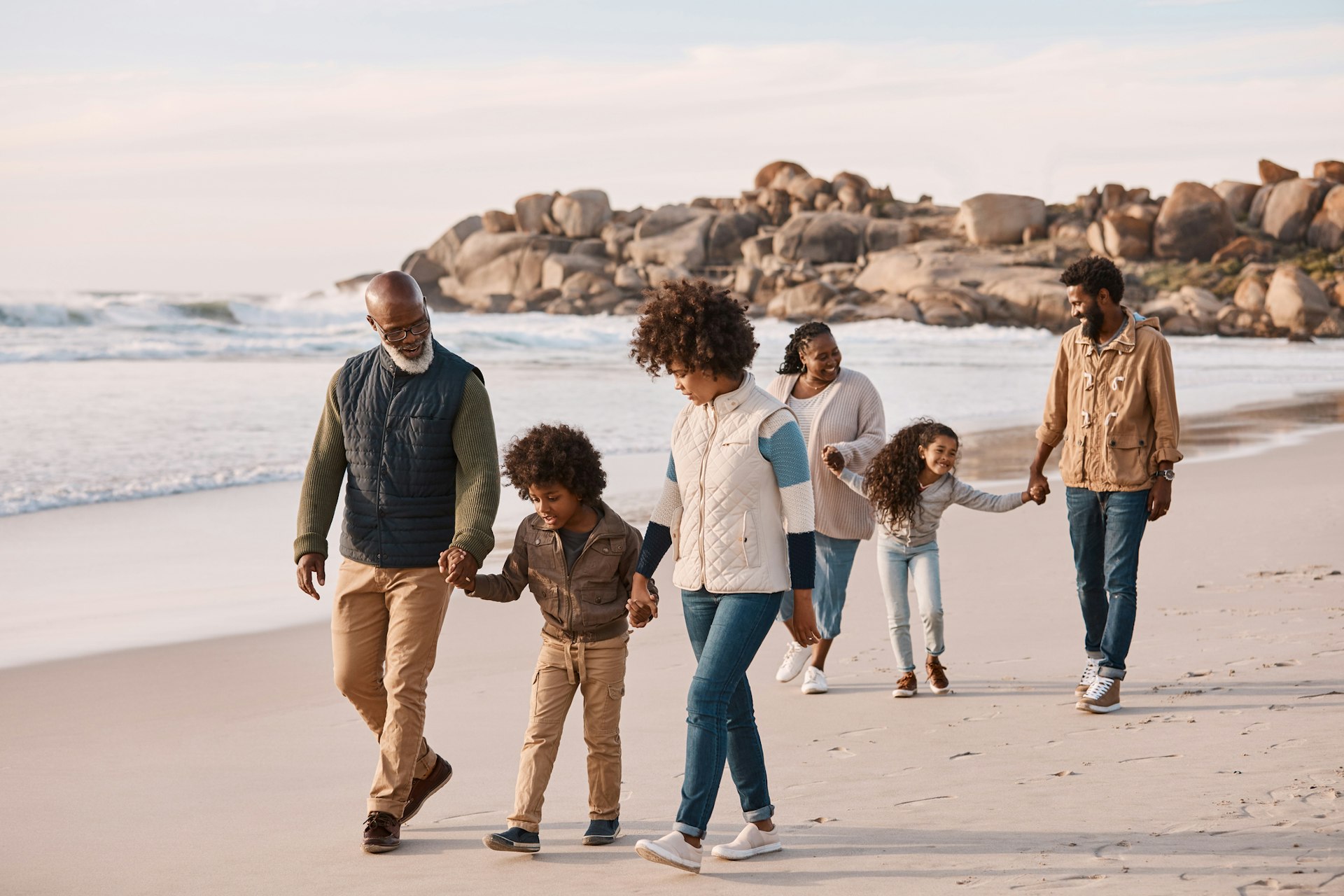 A multigenerational family stroll along a beach together