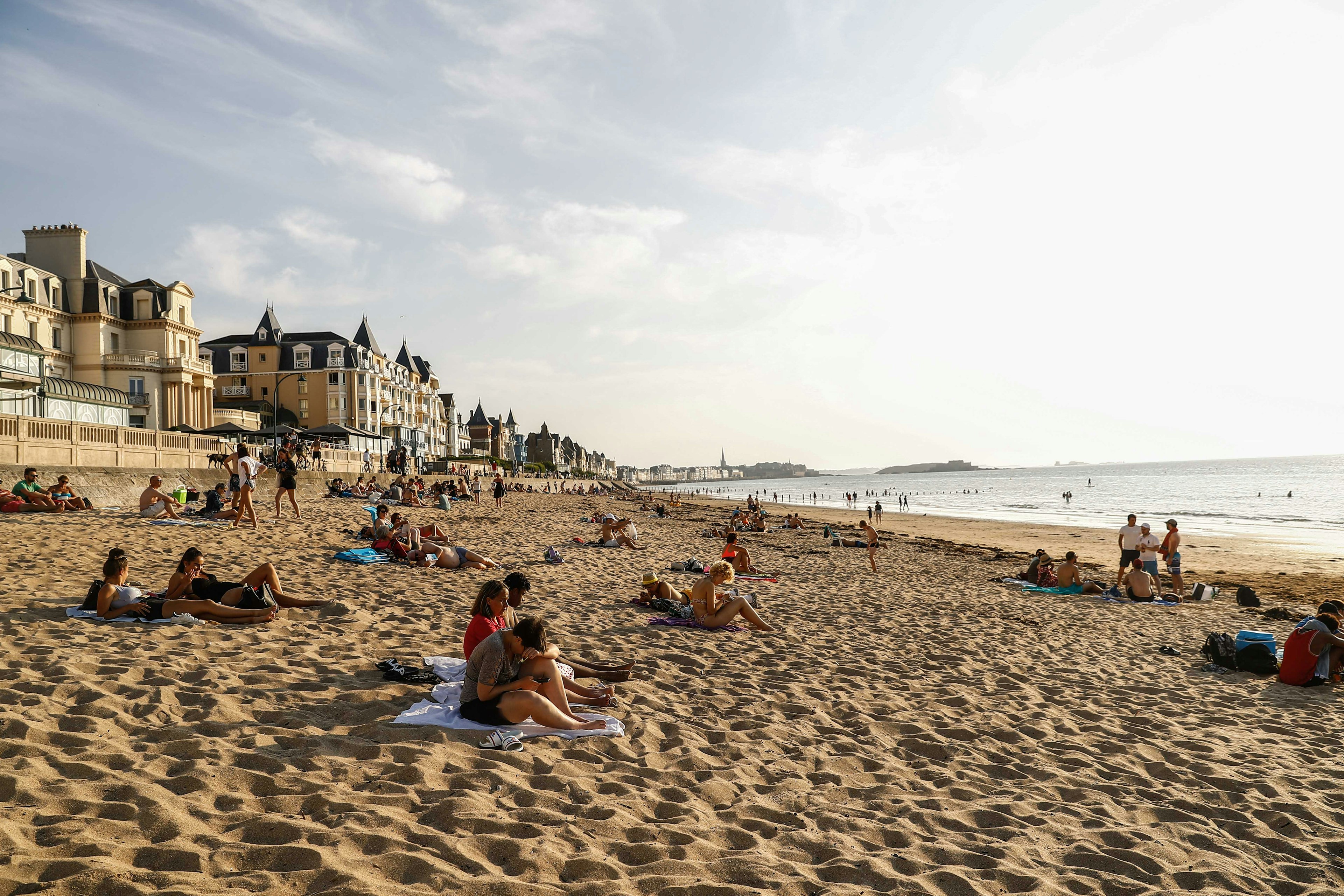 Tourists sunbathe on a beach by the sea in St-Malo, Brittany, France