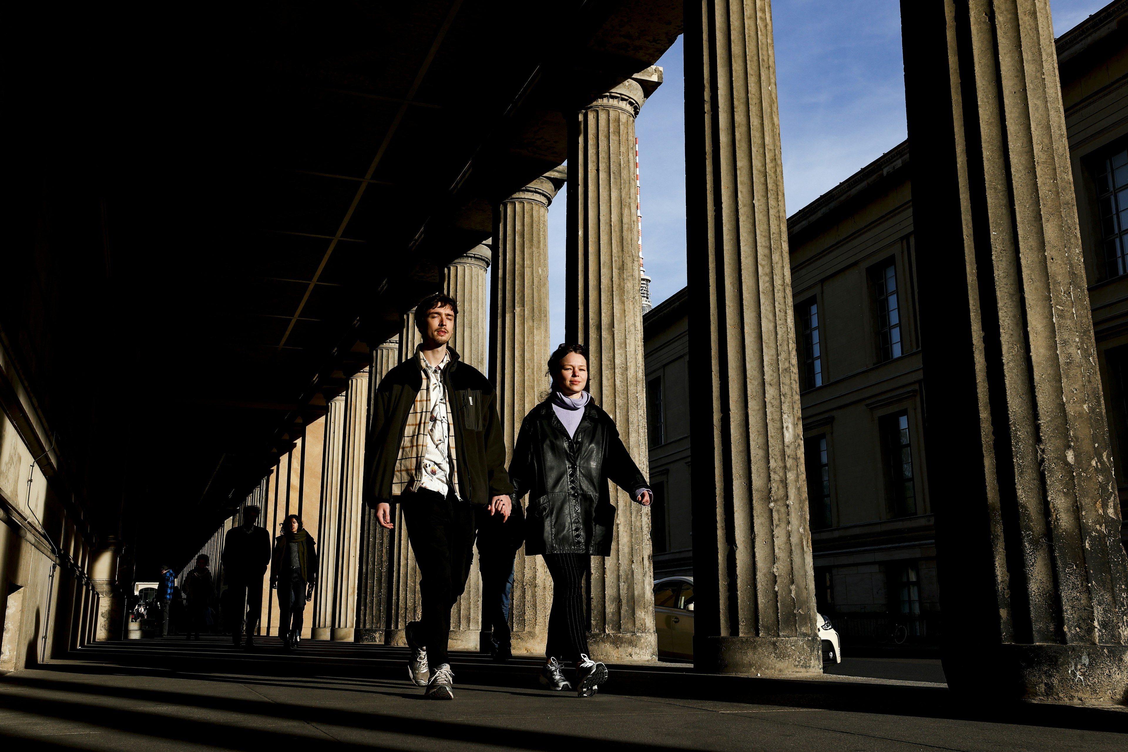 People walk down a classical colonnade on Museum Island, Berlin, Germany