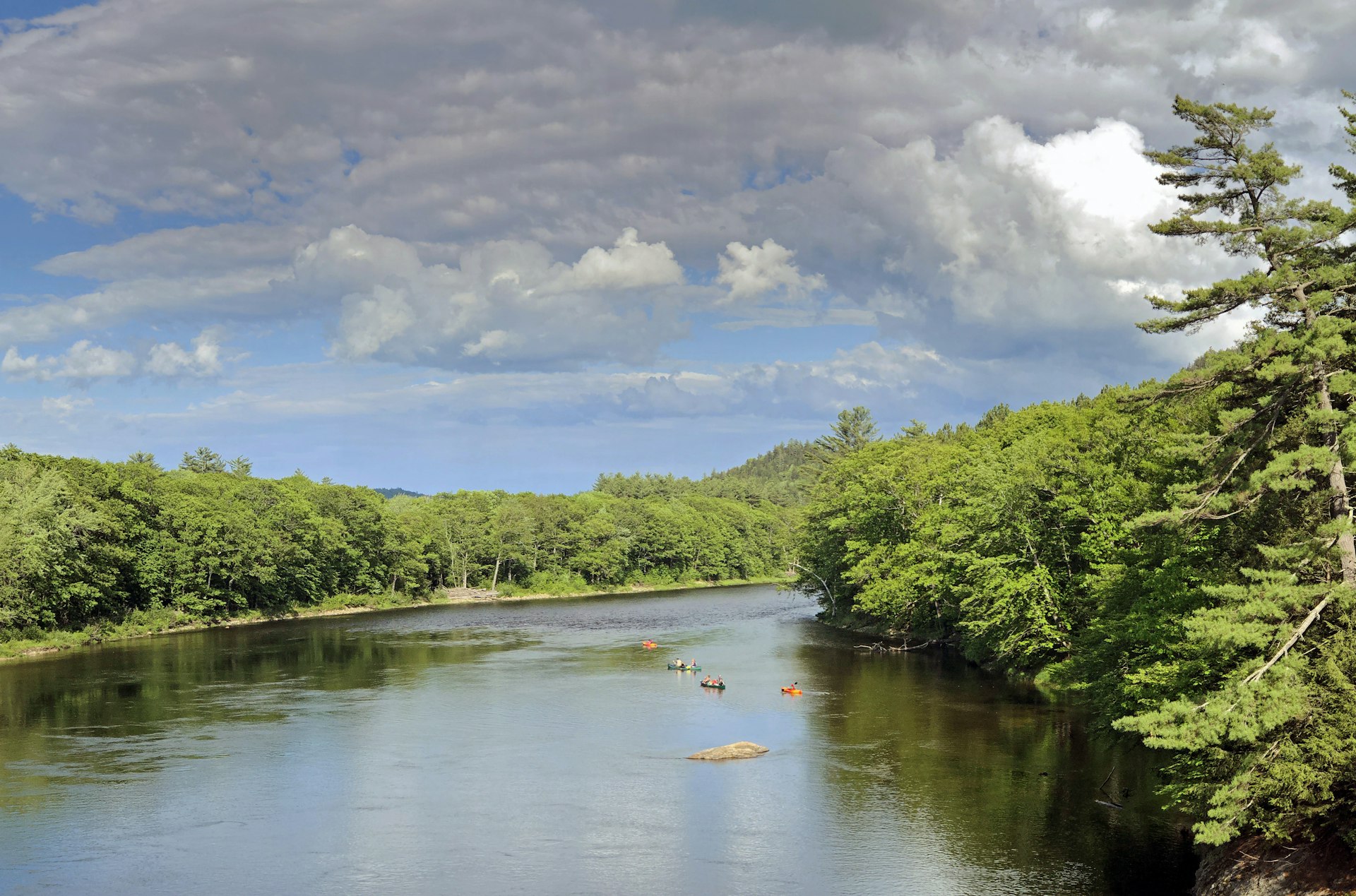 Family with kayaks and canoes going down the Androscoggin River during summer near Bethel, Maine