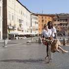 1267302408
Beautiful biracial couple riding bicycle in deserted Piazza Navona, Rome, Italy - stock photo
