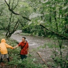Father and child hiking in rainy forest with river
1408819302