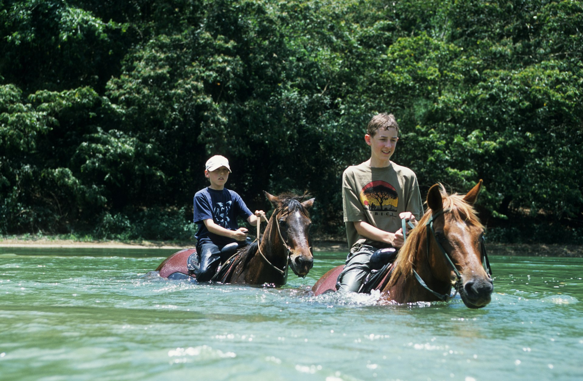 Children riding horses through a river