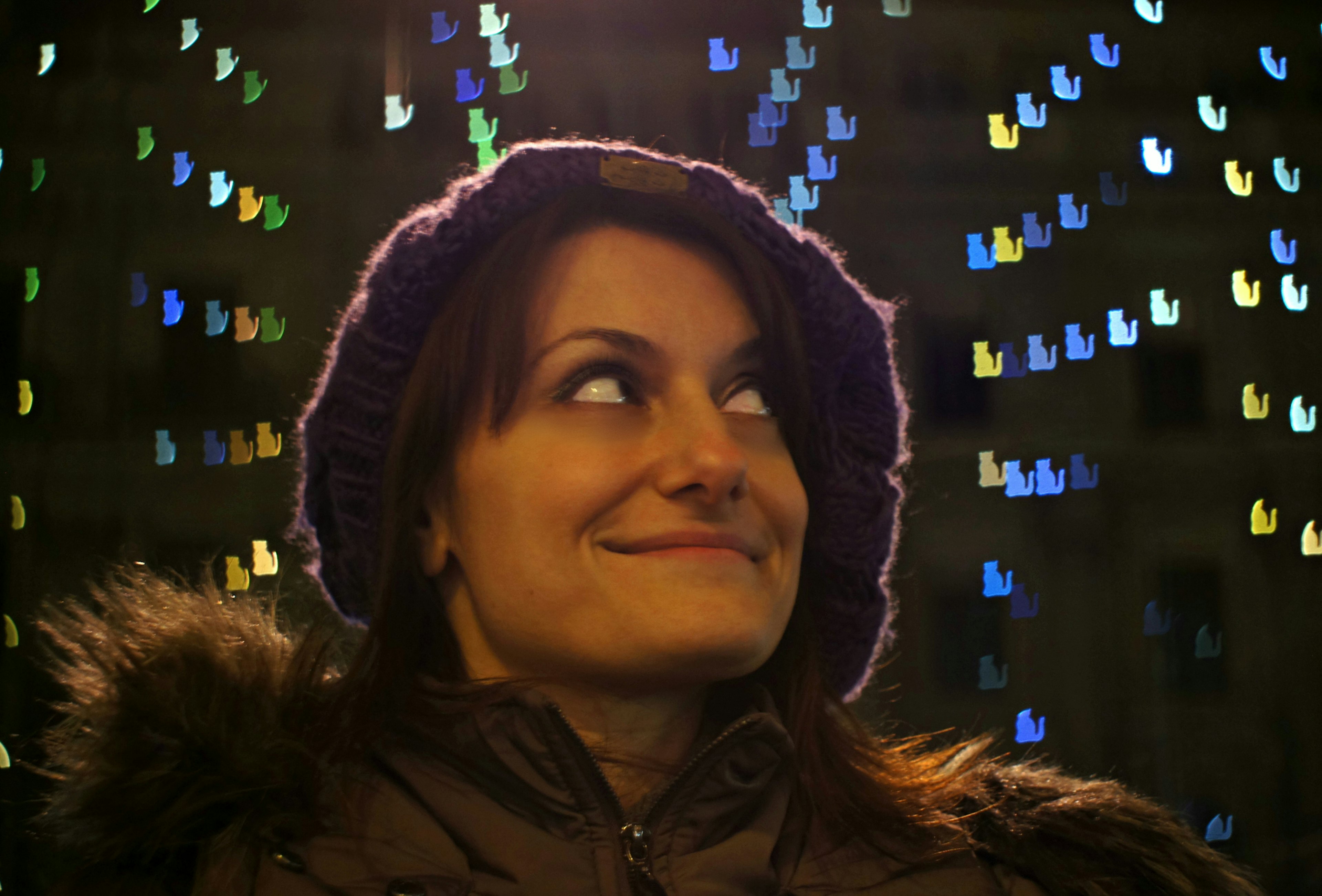 A woman smiles surrounded by Christmas lights in ü