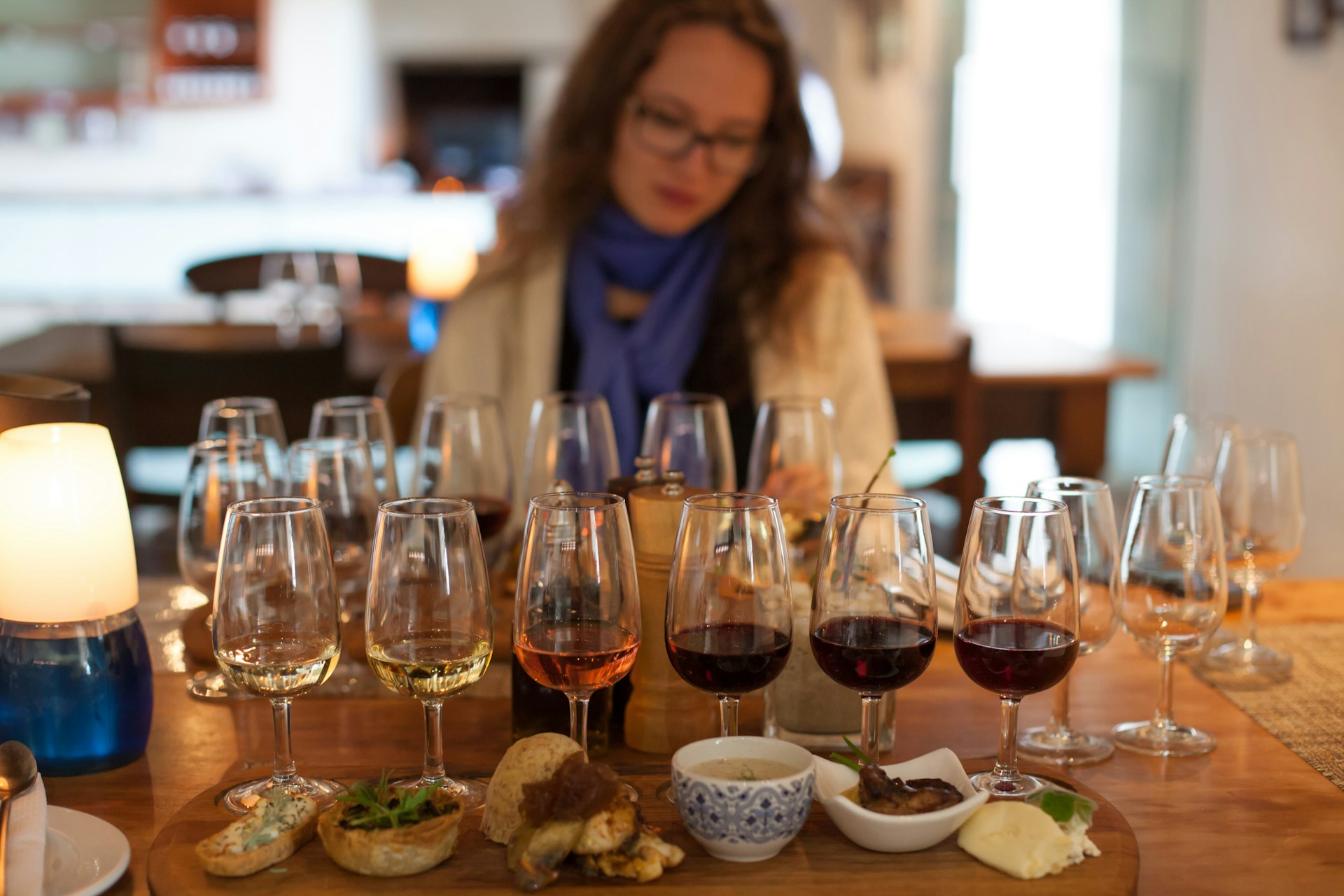 A woman sits in front of a series of wine glasses with a food pairing