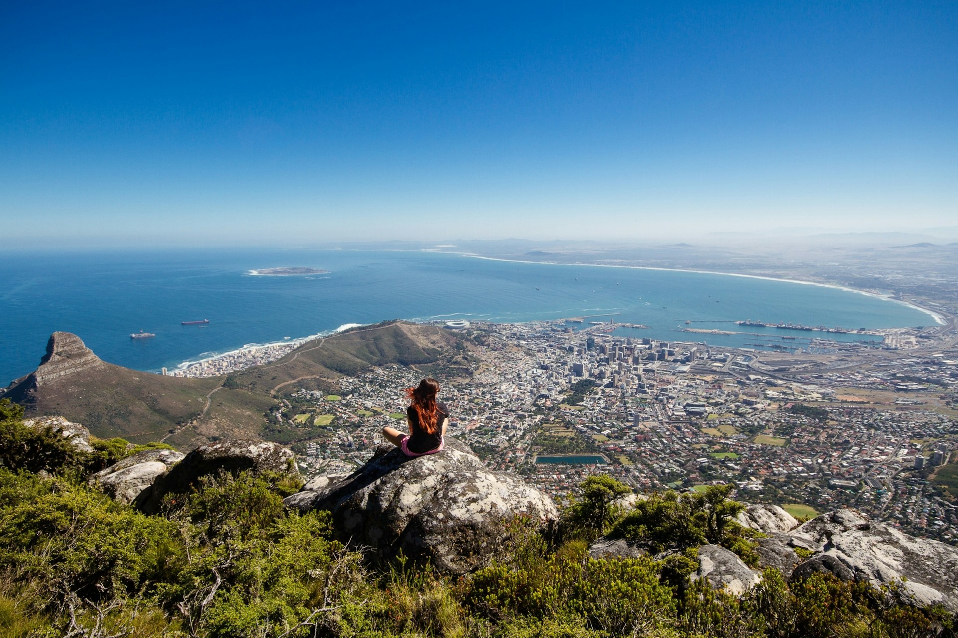 A woman sitting on Table Mountain with a view over all of Cape Town