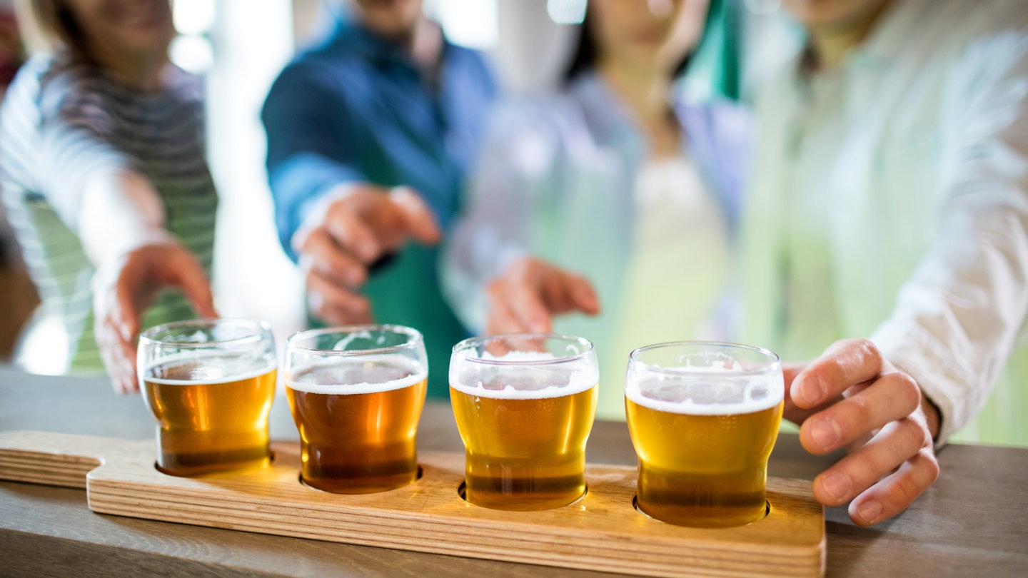 Friends reaching towards beer sampler at bar counter 653202164 Beer, Bar, Counter Top, Glass, Wood