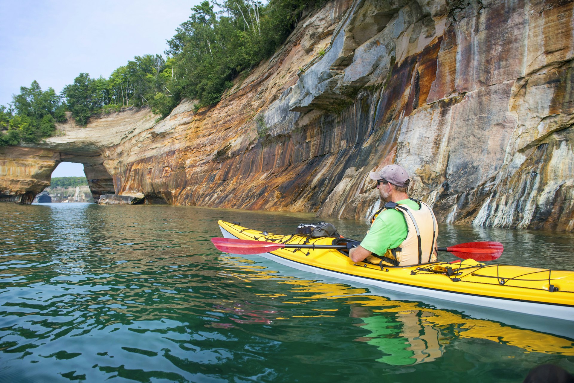 sea kayaker headed towards an arched rock along the Pictured Rocks National Lakeshore near Munising, Michigan