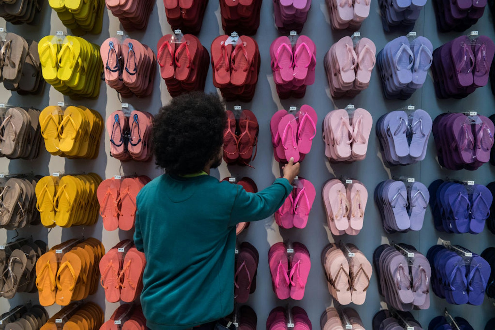 An employee touches a pair of Brazilian Havaianas flip-flops at a store in Sao Paulo