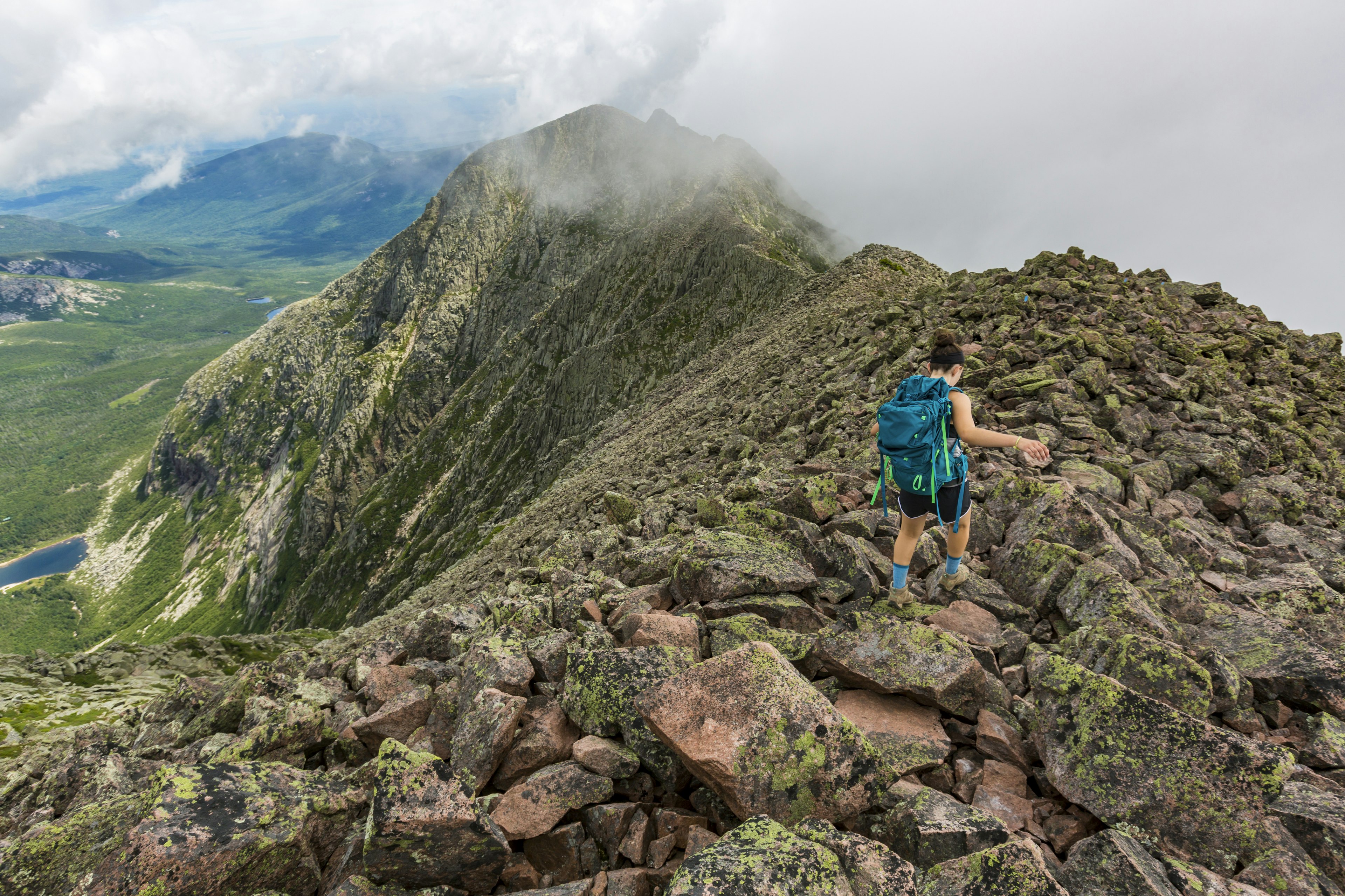 Teenage girl hiking along mountain ridge at Knife Edge Trail on Mount Katahdin in Baxter State Park, Maine